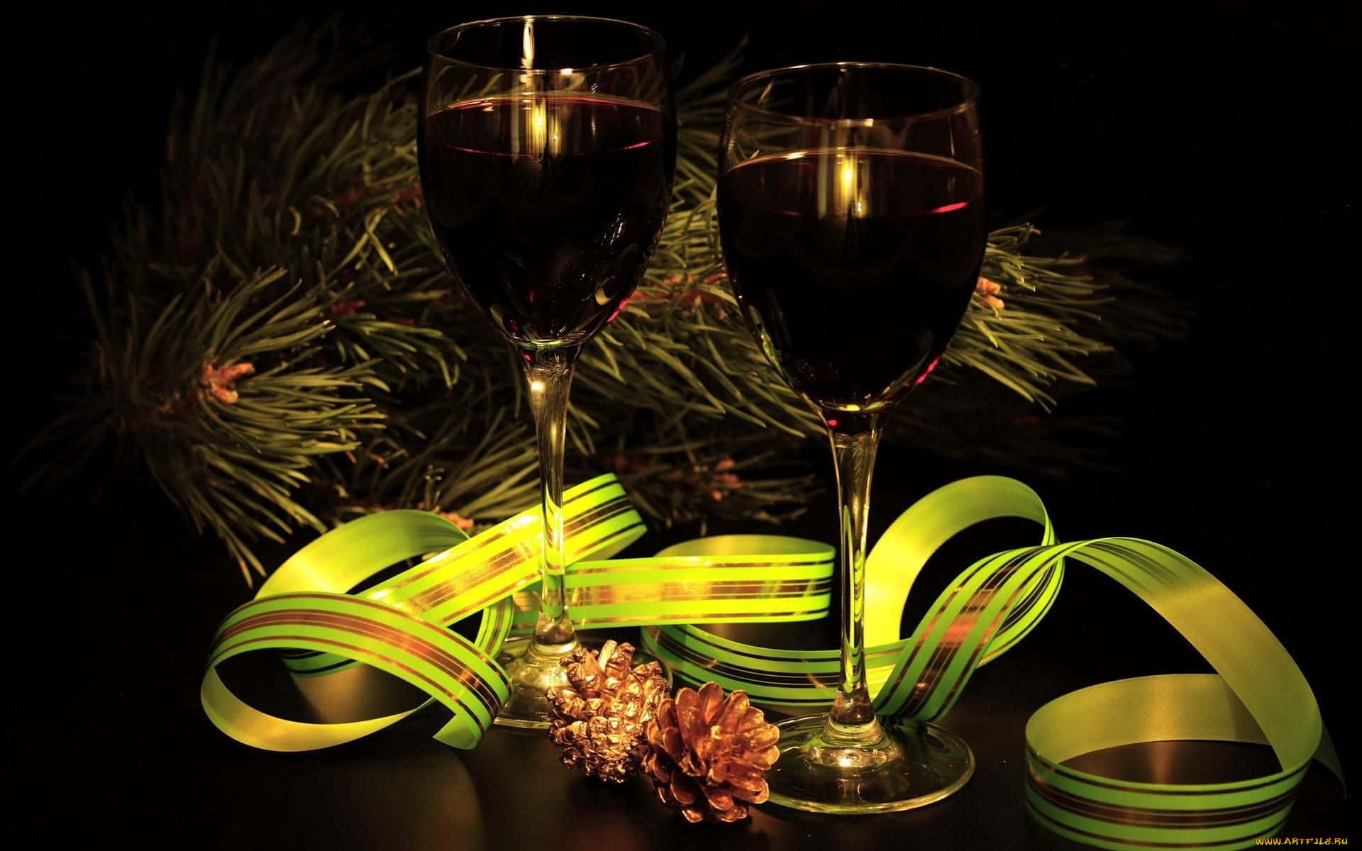 Black Wine 桌布 壁紙 — 兩個裝滿紅酒的酒杯放在松樹枝、松果和發光綠色絲帶旁邊，背景為黑色。