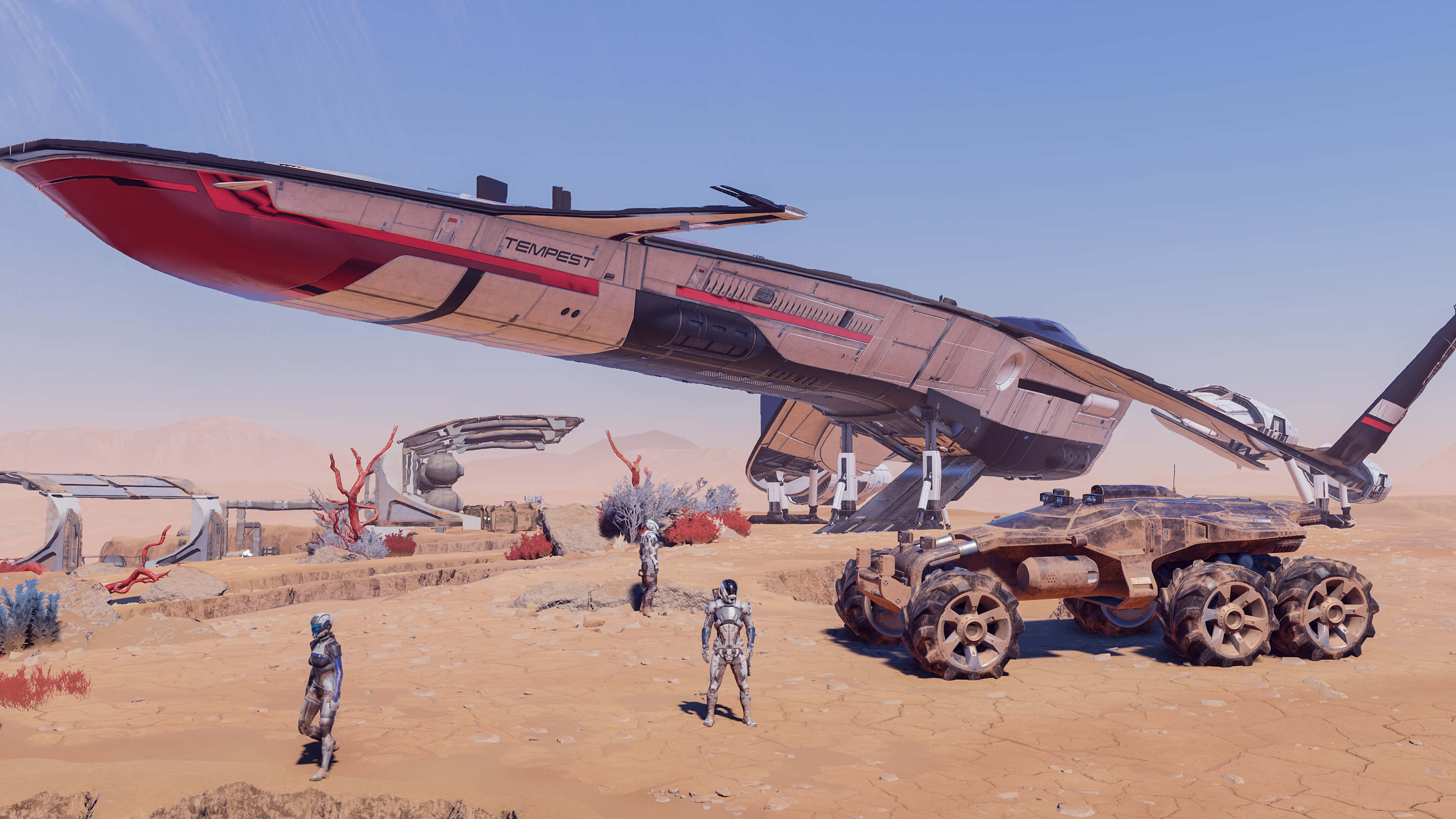 Mass Effect Andromeda 桌布 壁紙 — 兩個裝甲人物站在一架墜毀的未來太空船和堅固的越野車前，背景是荒蕪的沙漠和清澈的藍天。