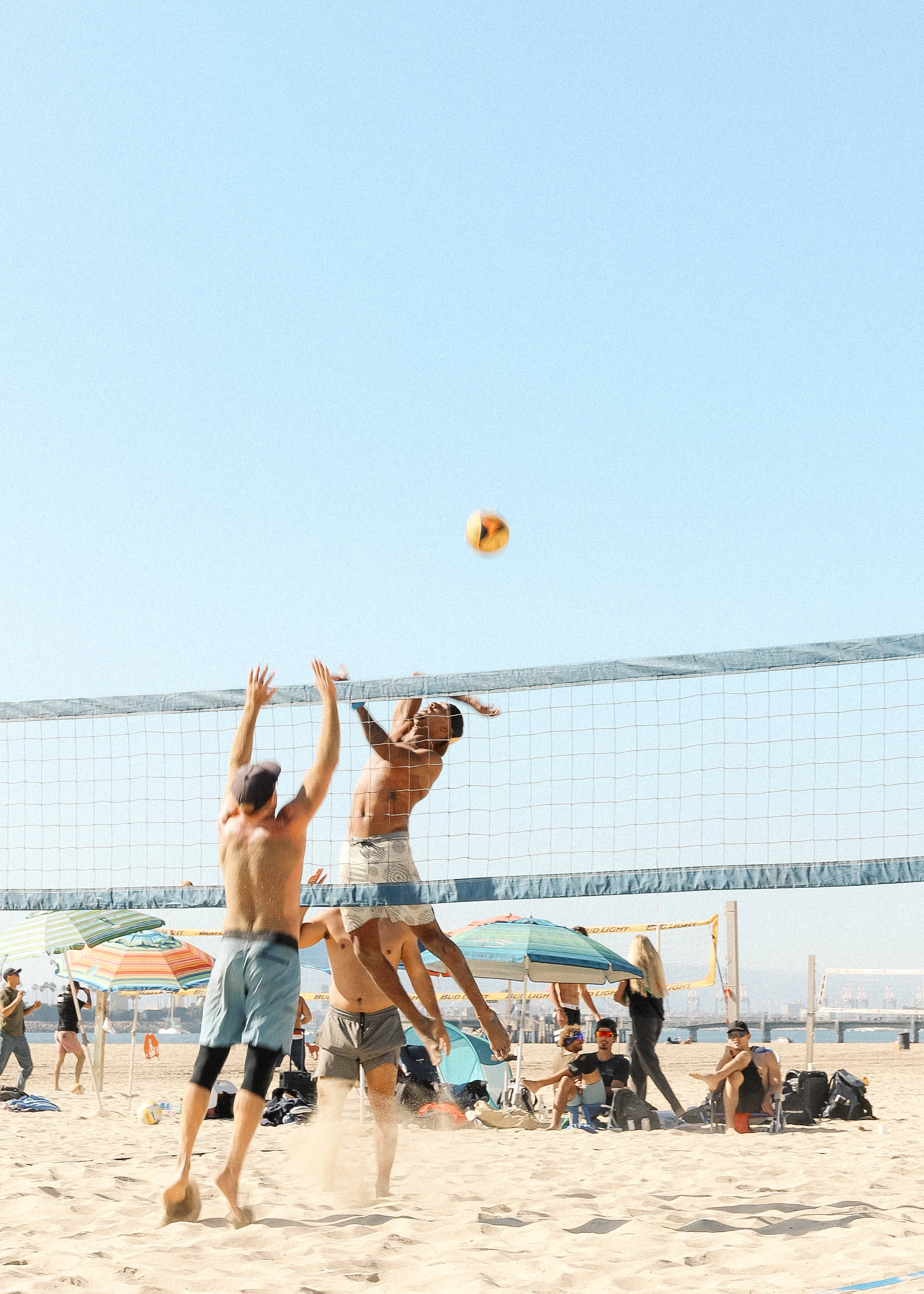 Volleyball 桌布 壁紙 — 兩個赤膊男子在晴朗的藍天下，在陽光明媚的海灘上強力躍向排球網。