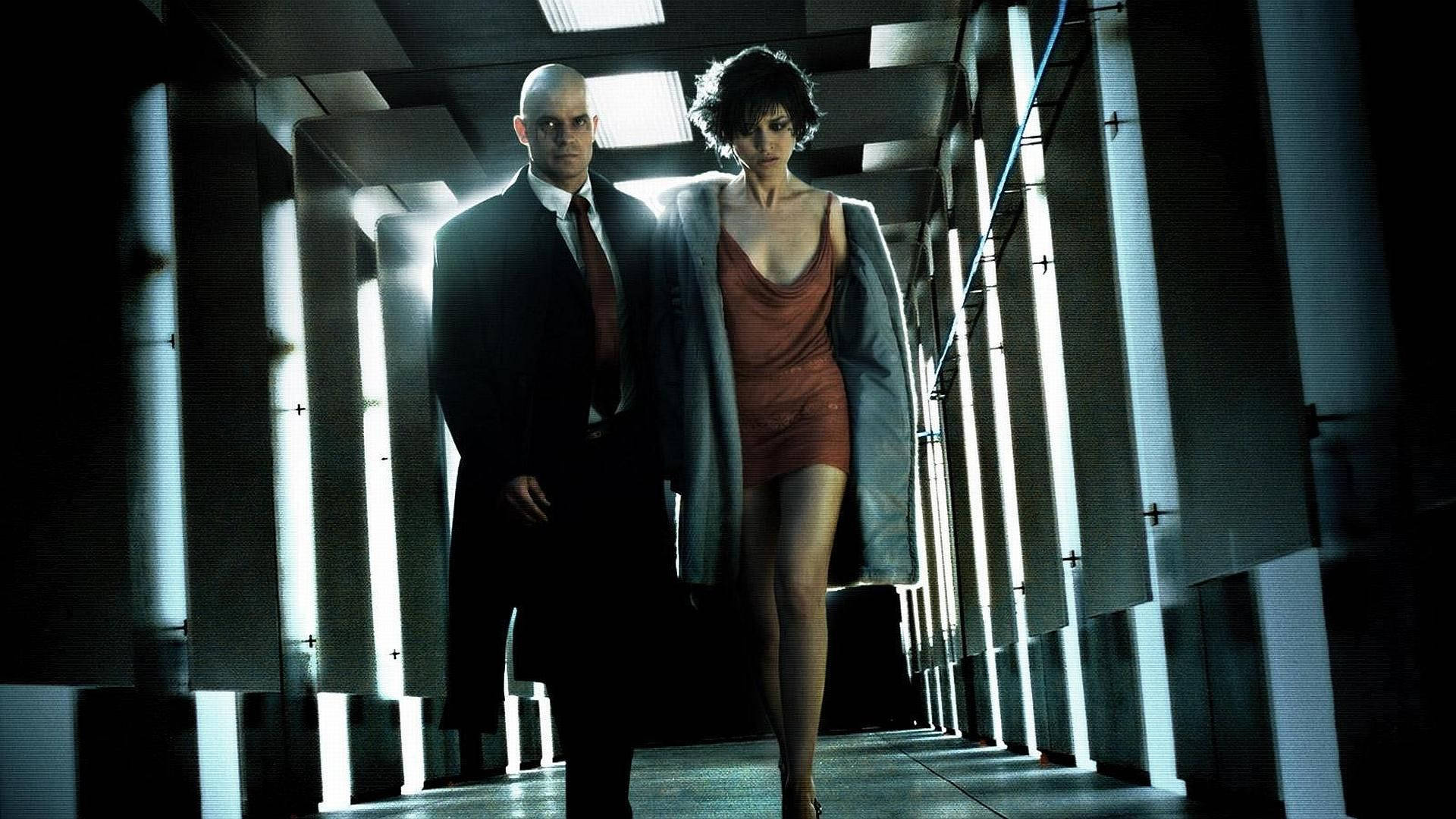 Hitman Absolution 桌布 壁紙 — 兩個身影走在一條光線刺眼的螢光燈走廊上，重複的幾何面板投下戲劇性的陰影。