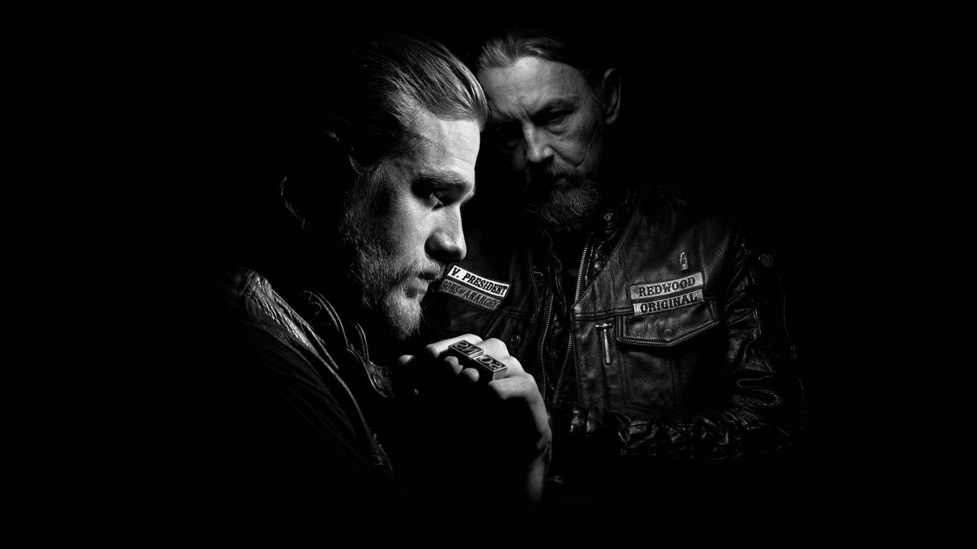 Sons Of Anarchy 桌布 壁紙 — 兩個身穿帶有徽章的皮背心的男人，在黑暗背景下以鮮明的黑白對比站立，其中一人手持香煙。