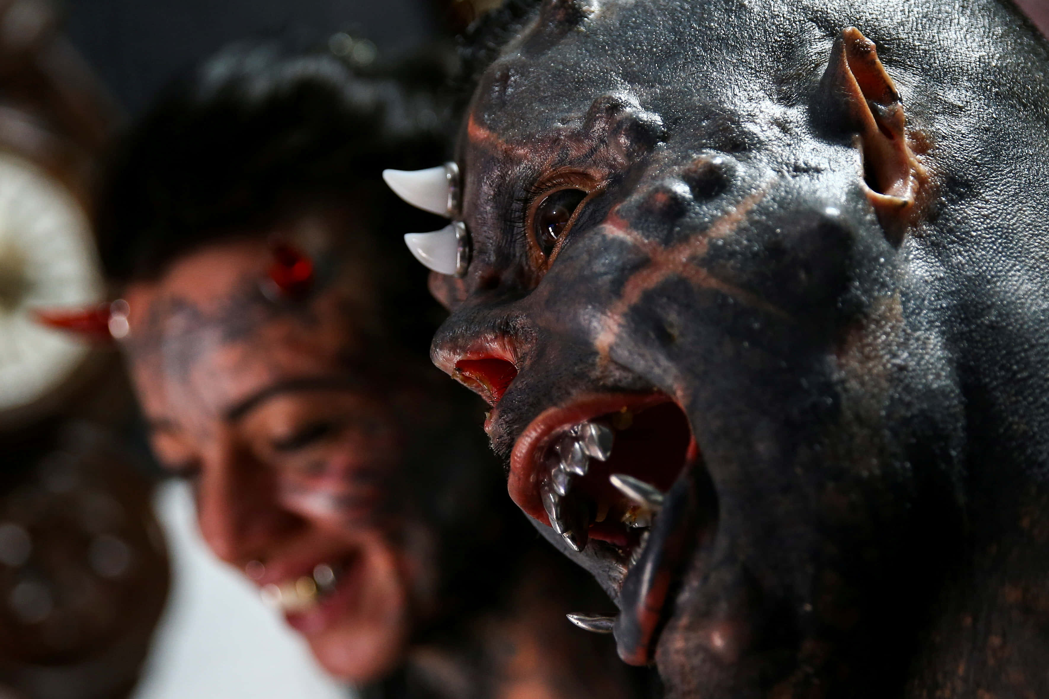 惡魔 桌布 壁紙 — 兩個身穿惡魔服飾、帶有黑色塗漆角及尖牙的人的特寫，一個微笑，另一個咆哮。