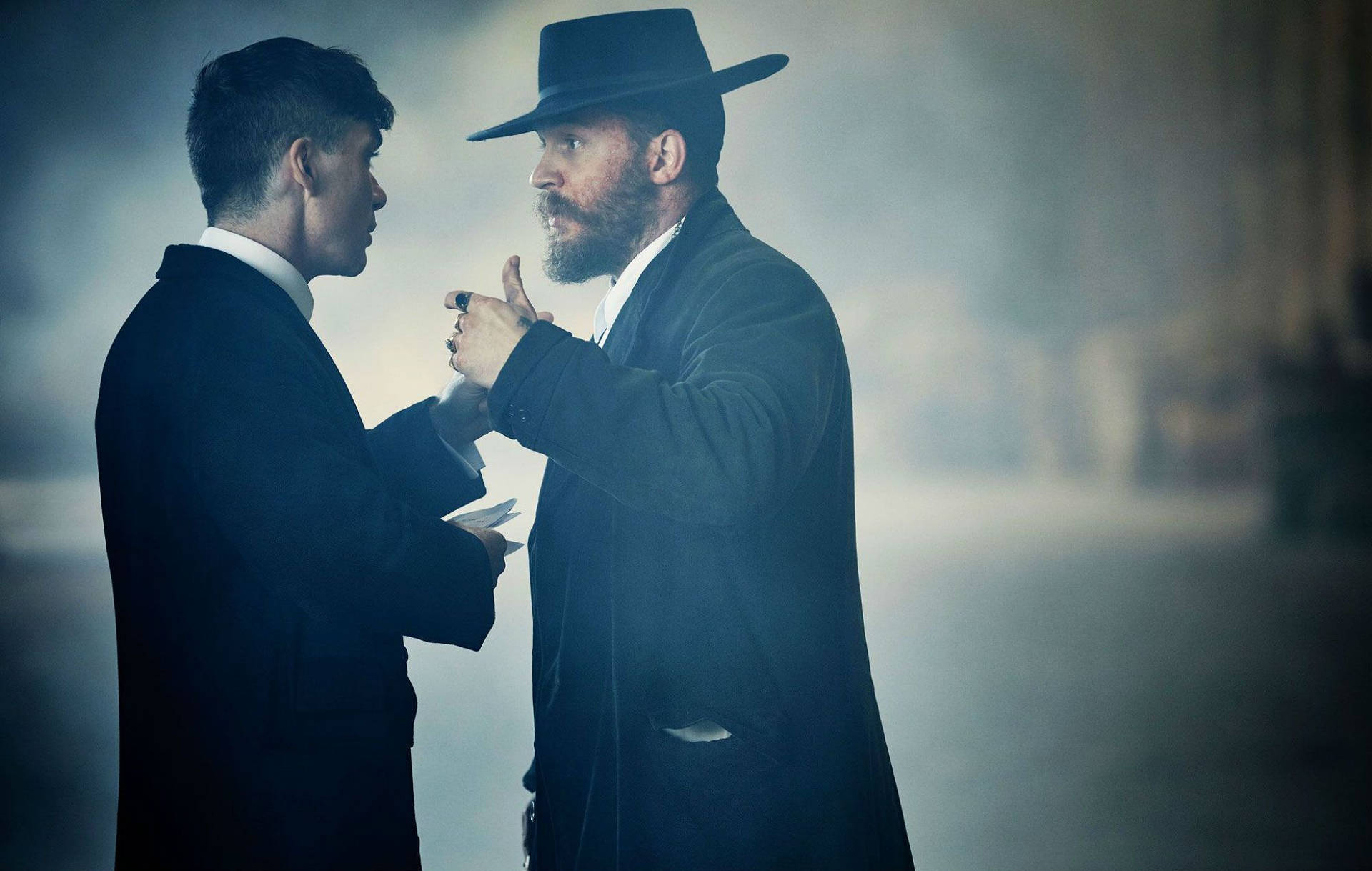 兩個穿西裝的男人在煙霧瀰漫的小巷中對峙。 — Peaky Blinders 壁紙