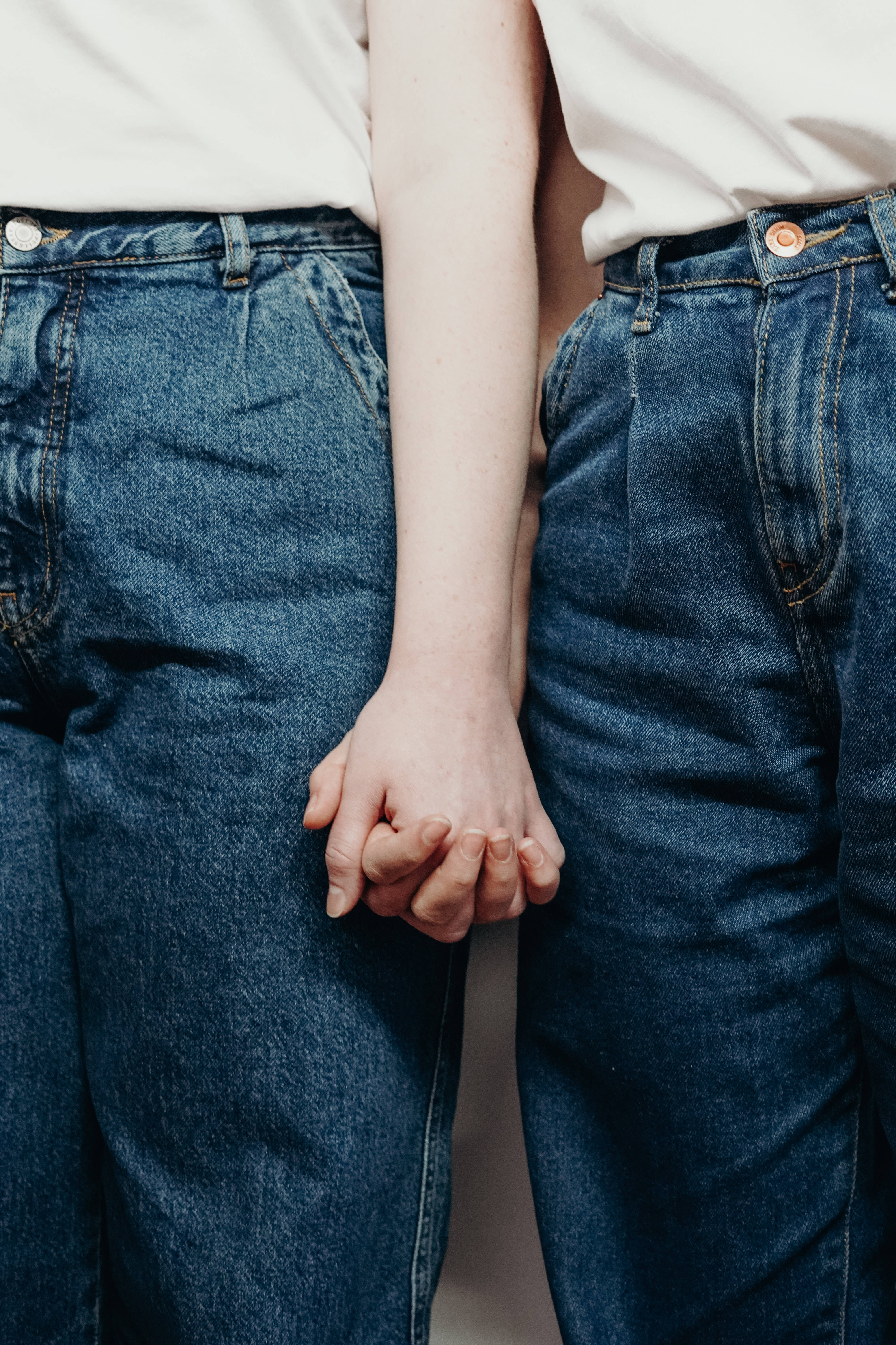 Denim 桌布 壁紙 — 兩個身穿牛仔褲的人緊緊握手，特寫鏡頭強調聯繫與親密。