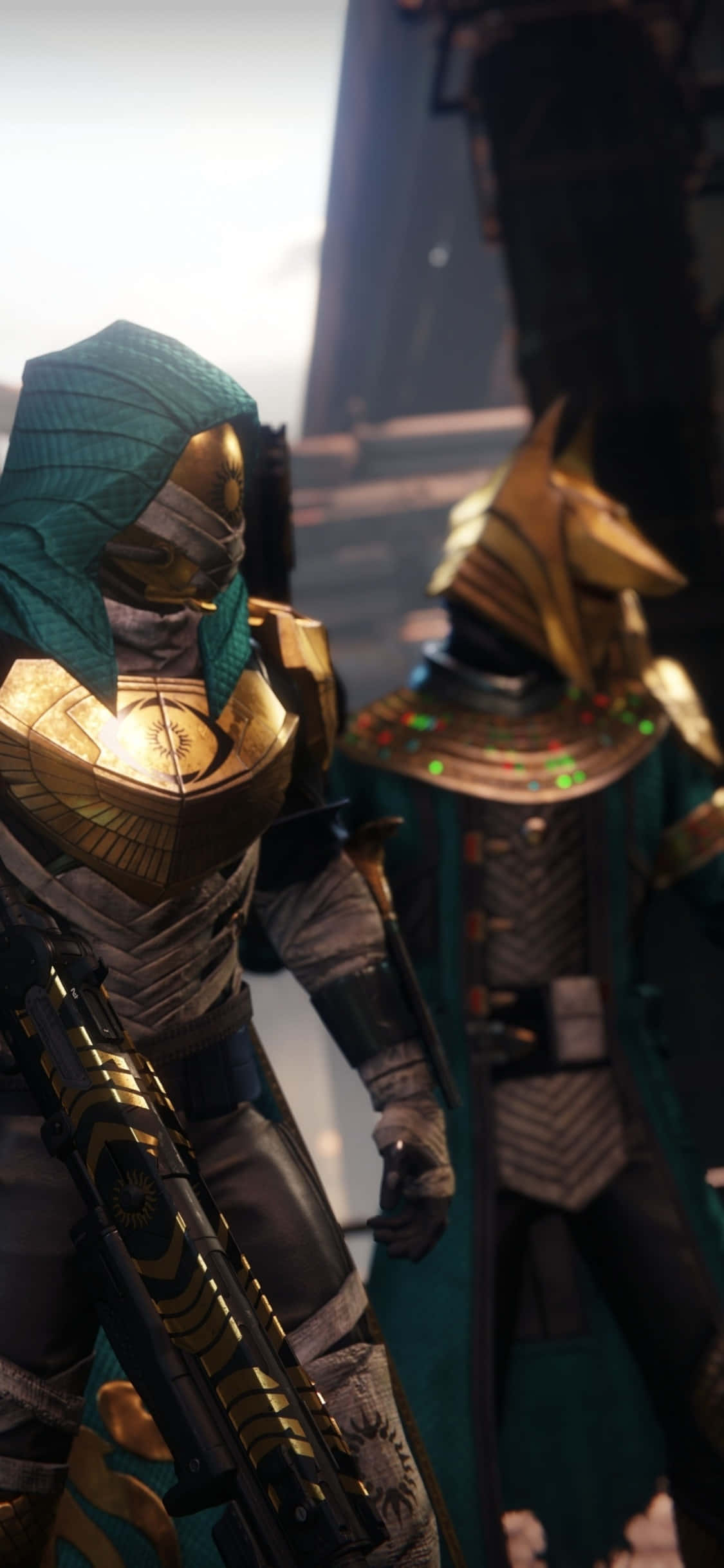iPhone Xs Destiny 2 桌布 壁紙 — 兩個身穿華麗金色和藍綠色裝備的裝甲人物，站在一個帶有發光裝飾的昏暗未來風格走廊中。