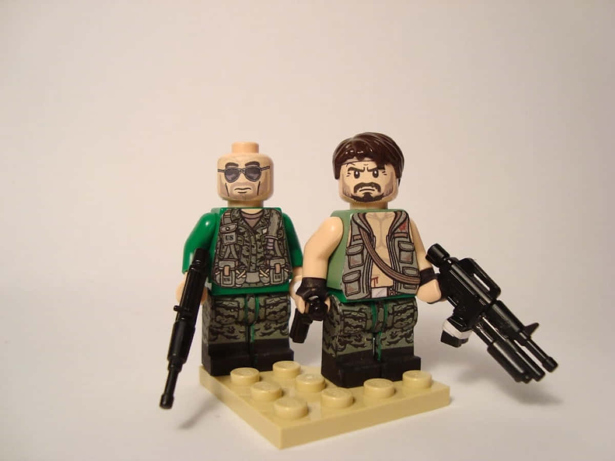 Frank Woods 桌布 壁紙 — 兩個身穿軍裝的LEGO人偶並排站立，手持槍械，位於淺褐色底板上，背景為純白色。