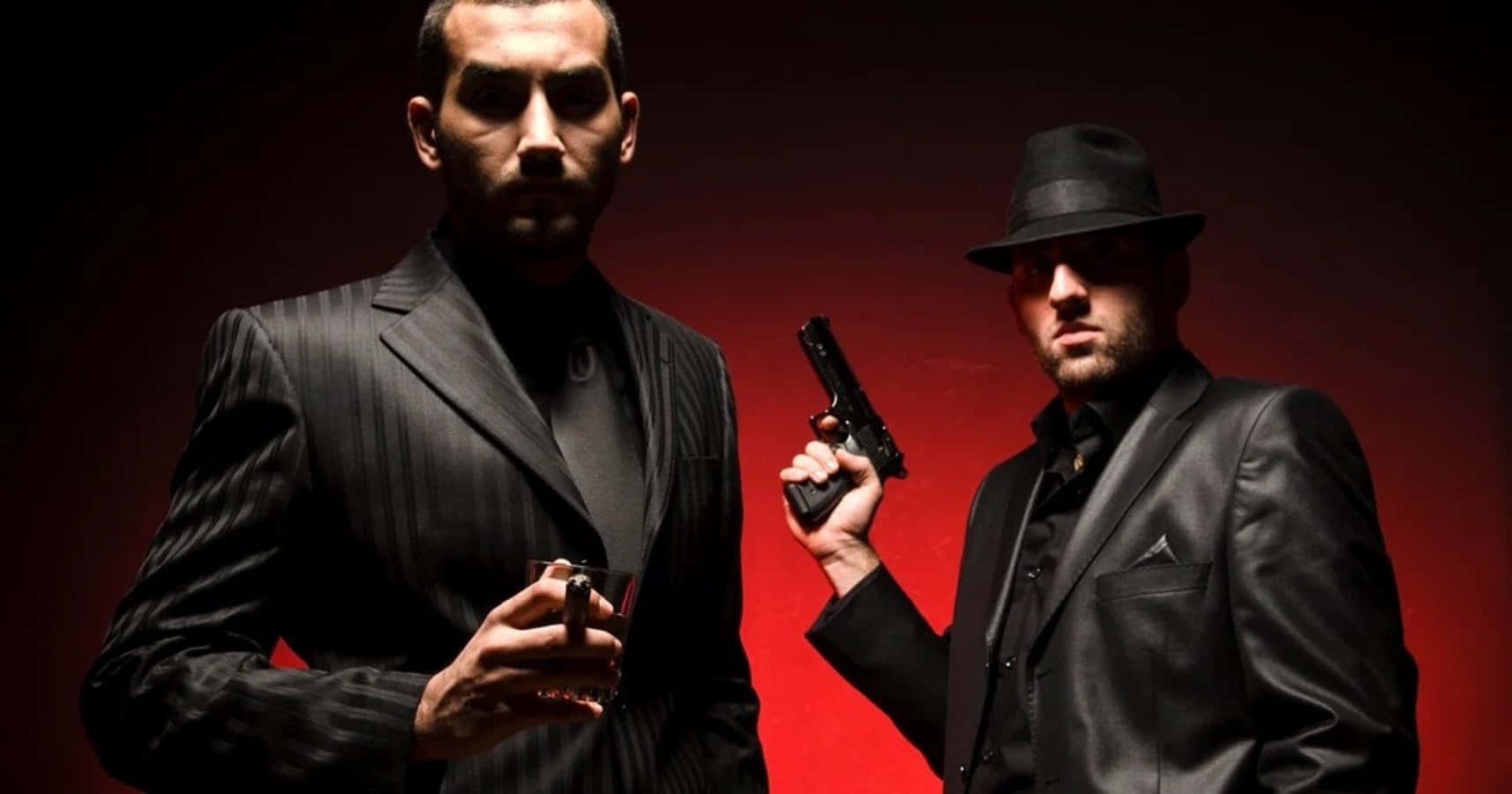 Mafia 桌布 壁紙 — 兩個身穿黑色西裝的男人站在深紅色背景前，一個拿著槍，另一個拿著香煙，散發出強烈的威脅感。