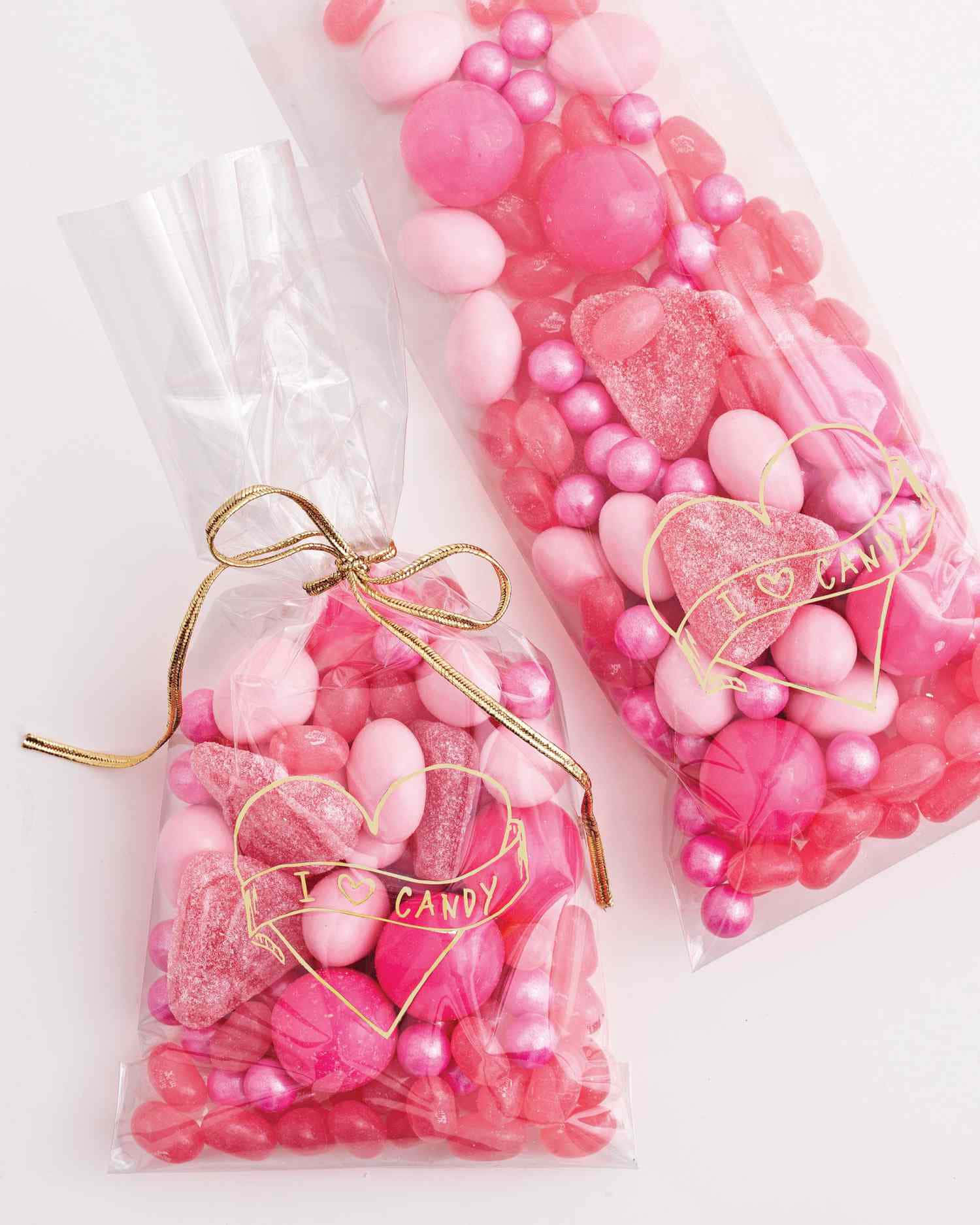 Pink Candy 桌布 壁紙 — 兩個透明玻璃紙袋，裝滿各種粉紅色糖果，用金色絲帶和心形「I ❤️ CANDY」標籤紮起。