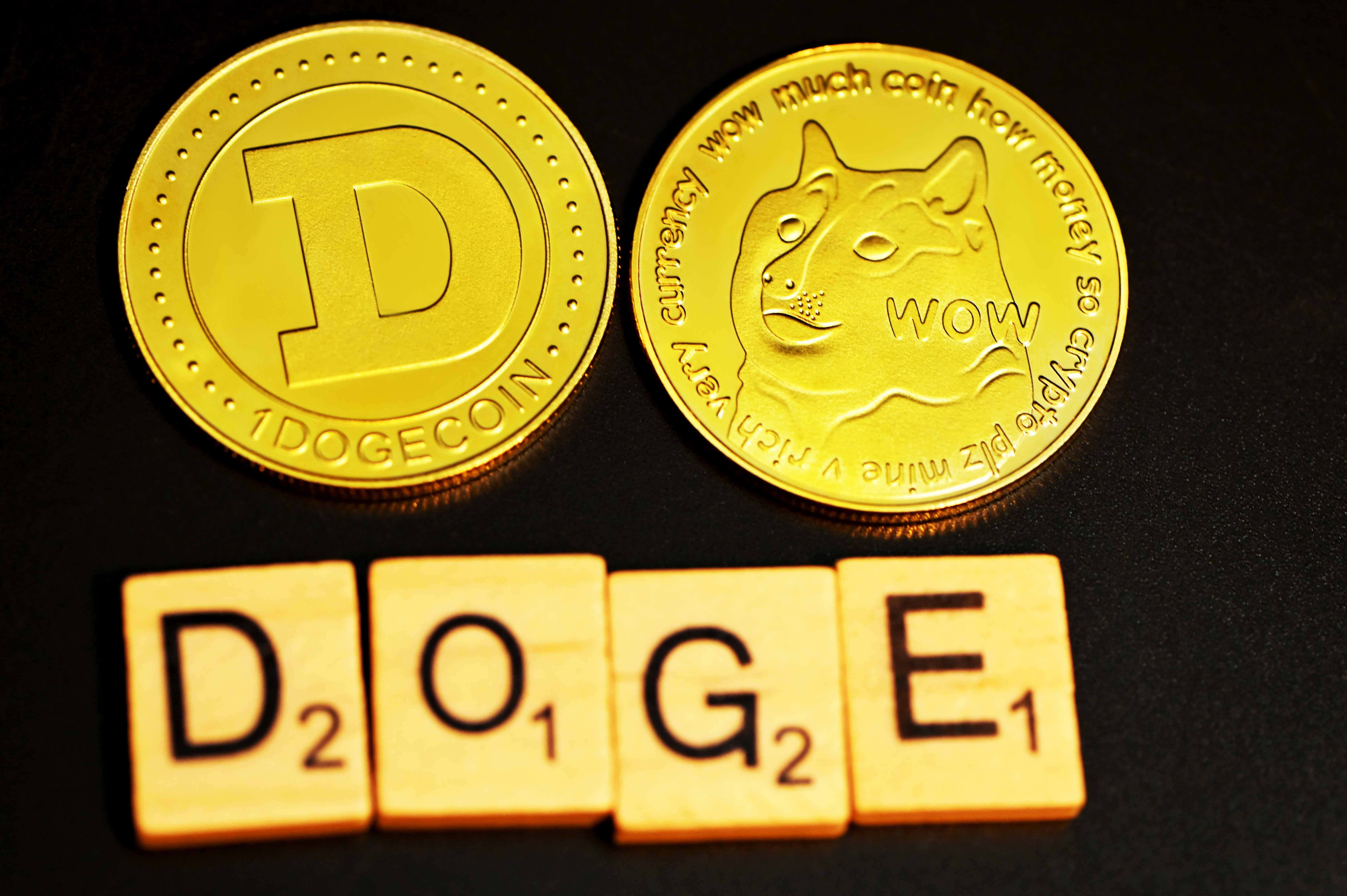 Dogecoin 桌布 壁紙 — 兩個金色 Dogecoin 代幣和拼出 DOGE 的木製 Scrabble 字母牌，在溫暖燈光下放置於深色表面上。