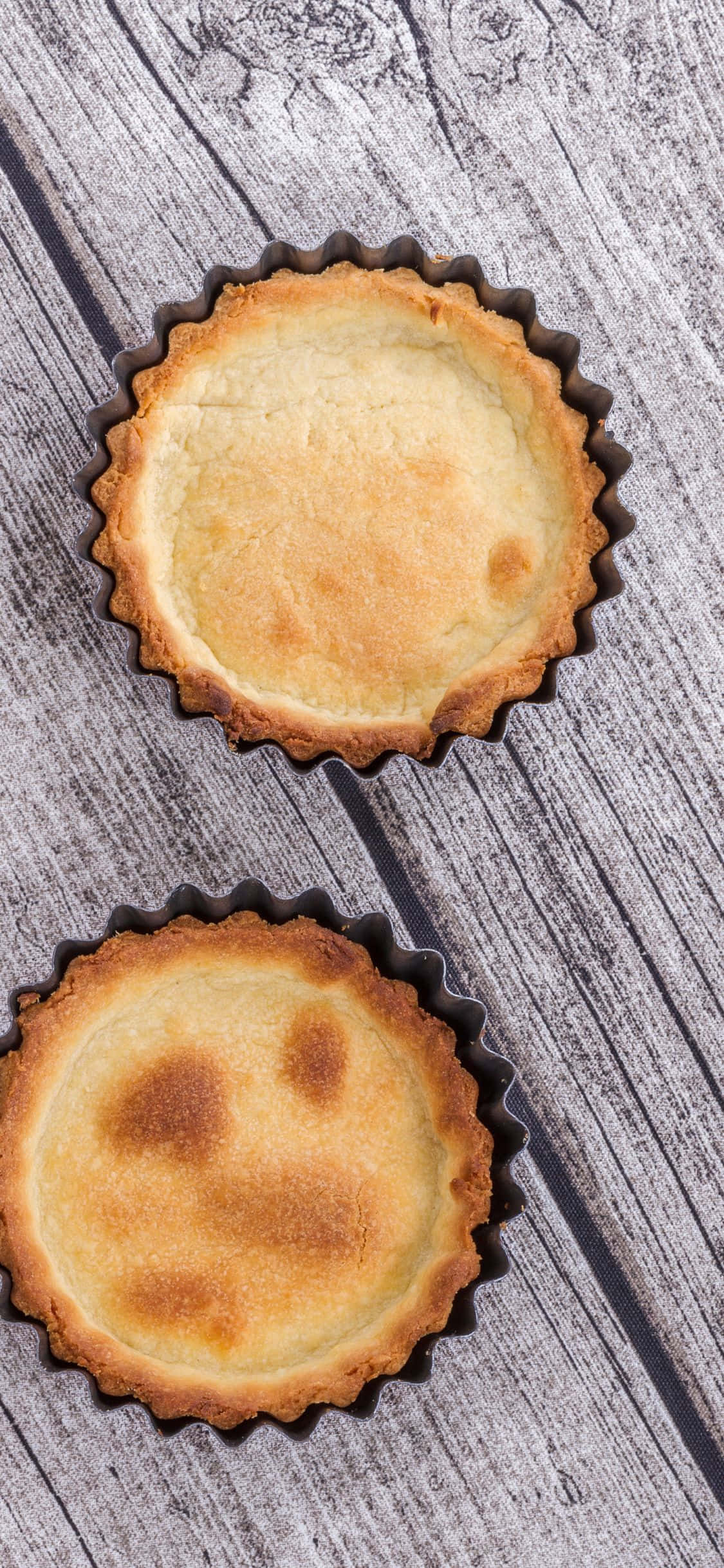 Pastry 桌布 壁紙 — 兩個金黃色的塔殼放在金屬杯中，置於經風化的灰色木質表面上。