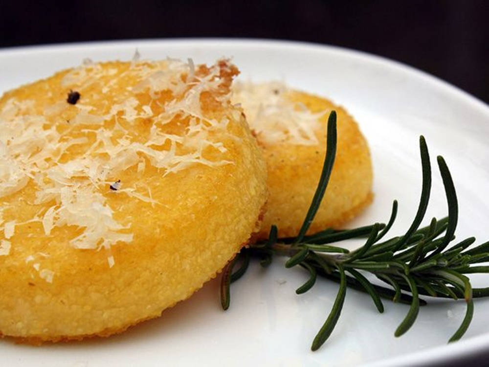 Rosemary 桌布 壁紙 — 兩個金黃色的玉米糕，上面撒有磨碎的起司，並用新鮮迷迭香點綴，放在白色盤子上。