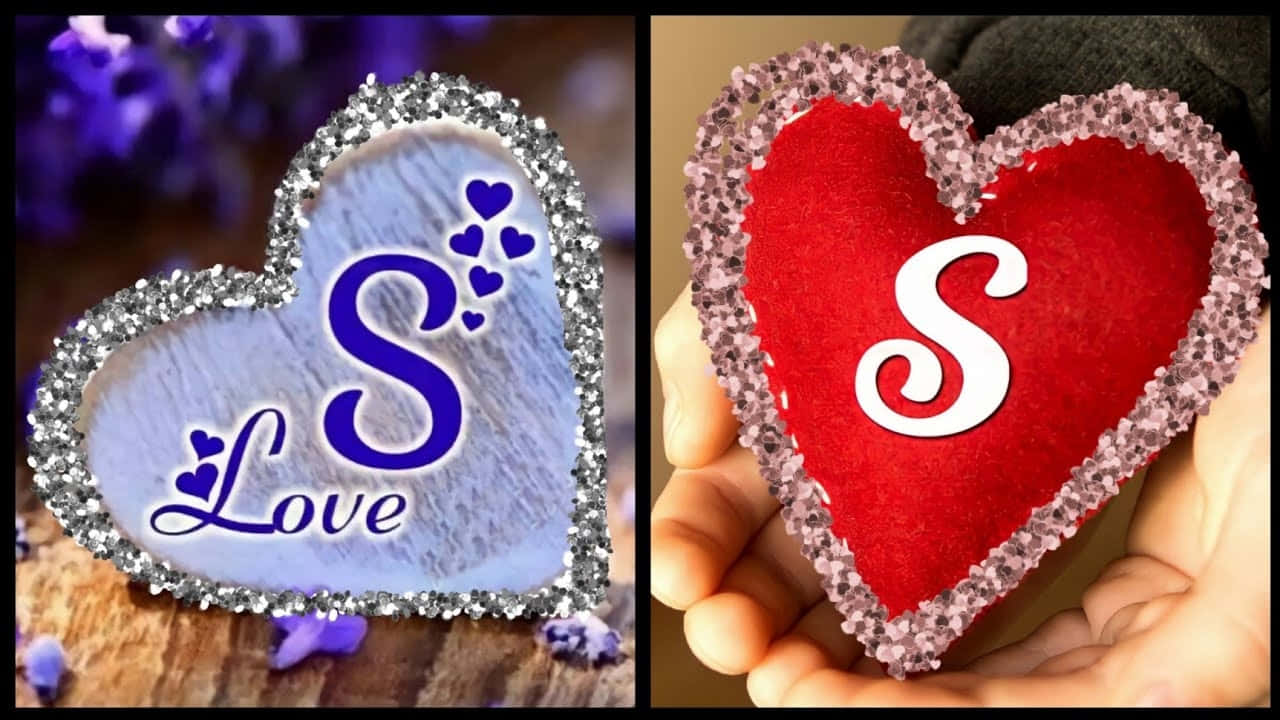 S 桌布 壁紙 — 兩個閃閃發光的心形手工藝品，一個藍色帶有「S Love」，另一個紅色握在手中，兩者都飾有閃爍的邊緣。