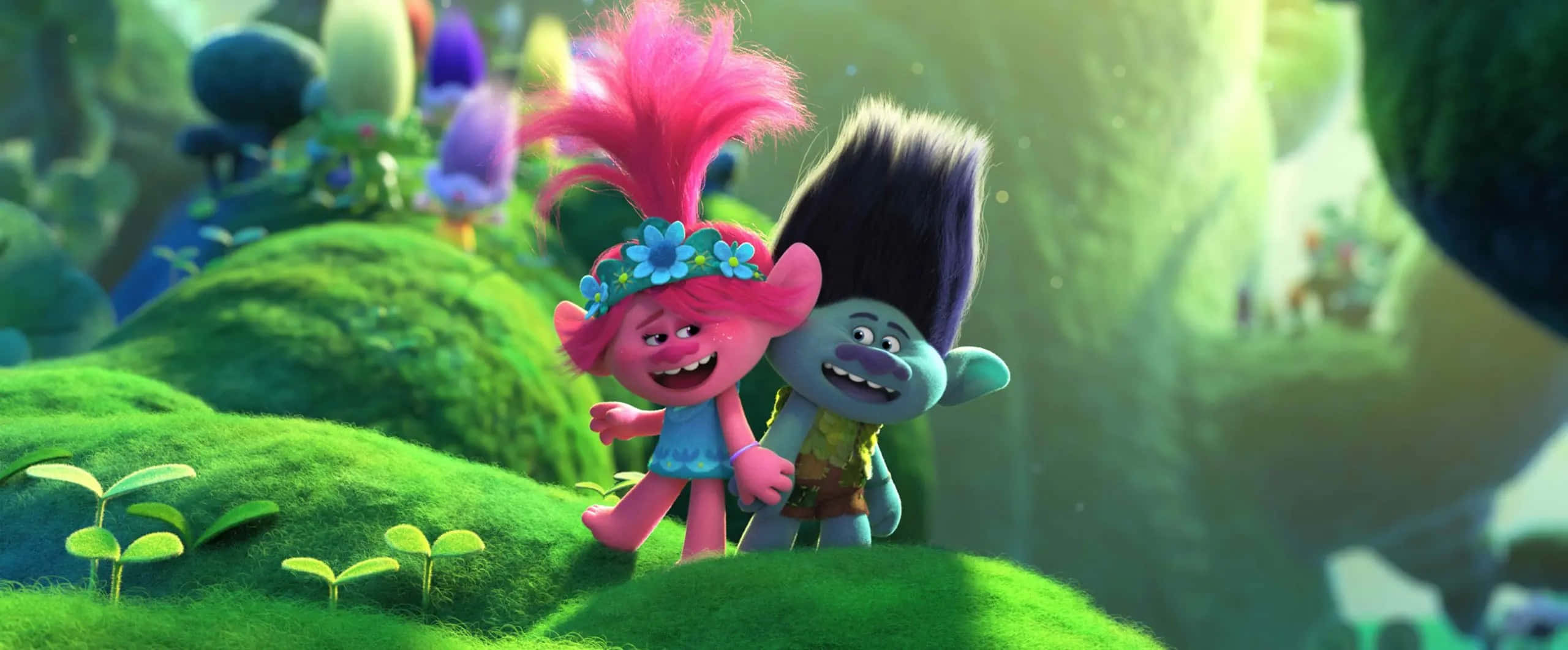 Trolls World Tour 桌布 壁紙 — 兩個開朗的巨魔角色，擁有鮮豔的粉紅色和黑色頭髮，站在色彩繽紛的幻想森林中長滿苔蘚的綠色山丘上。