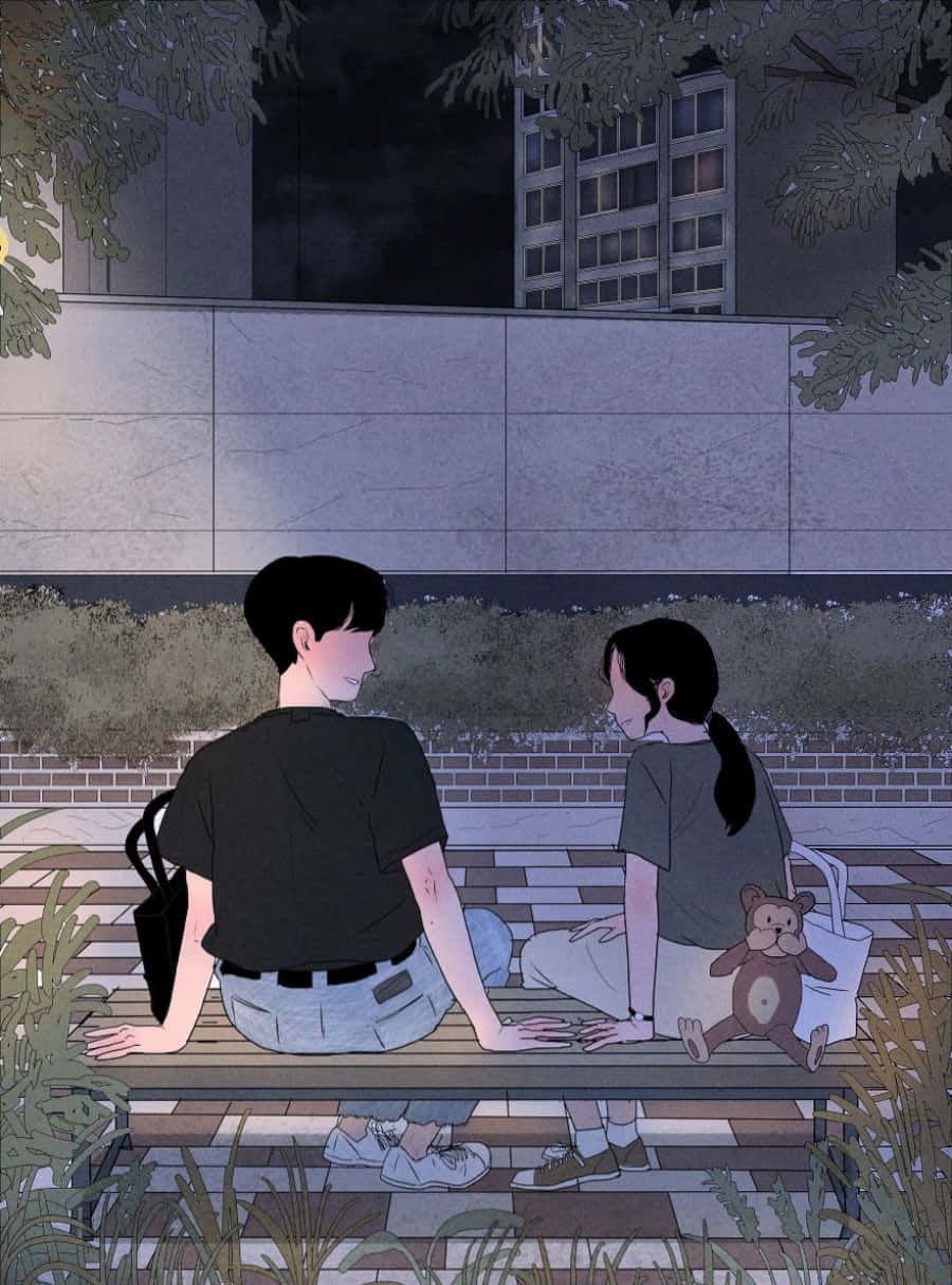 Couple Cartoon 桌布 壁紙 — 兩個青少年夜晚坐在城市公園的長椅上，周圍有樹木和建築物。