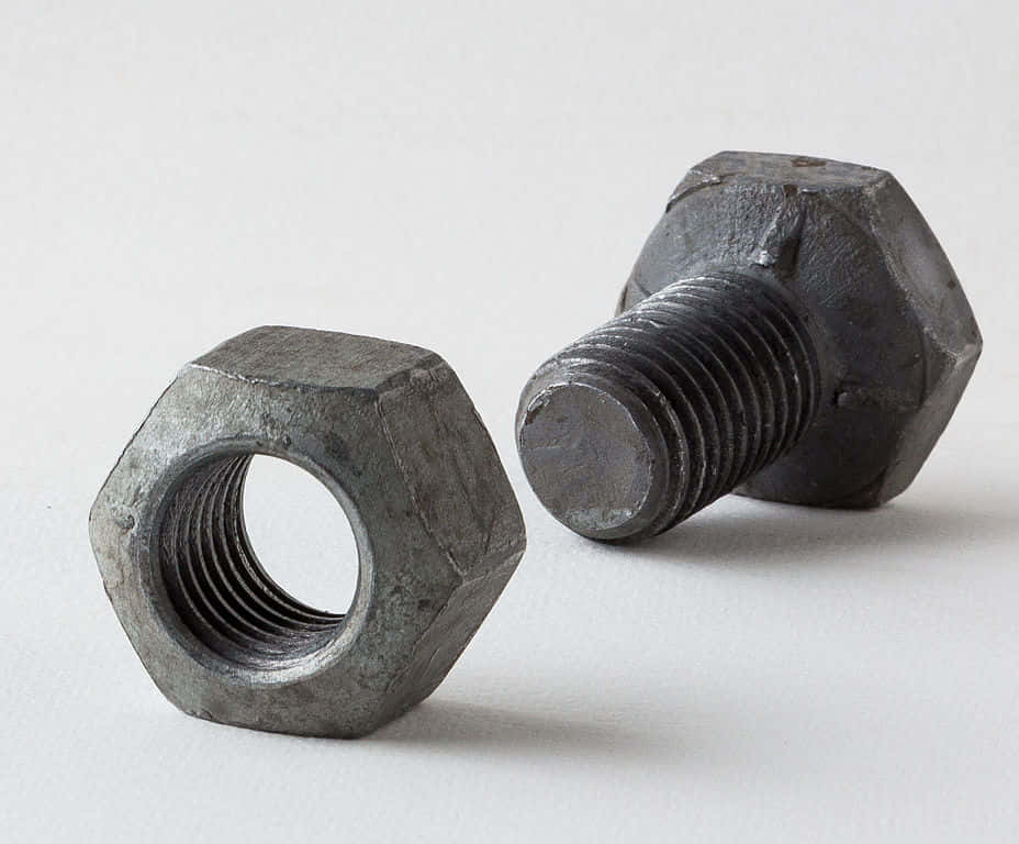 Shapes 桌布 壁紙 — 兩個風化的六角螺栓和螺母放在白色平面上，顯示工業紋理和金屬光澤。