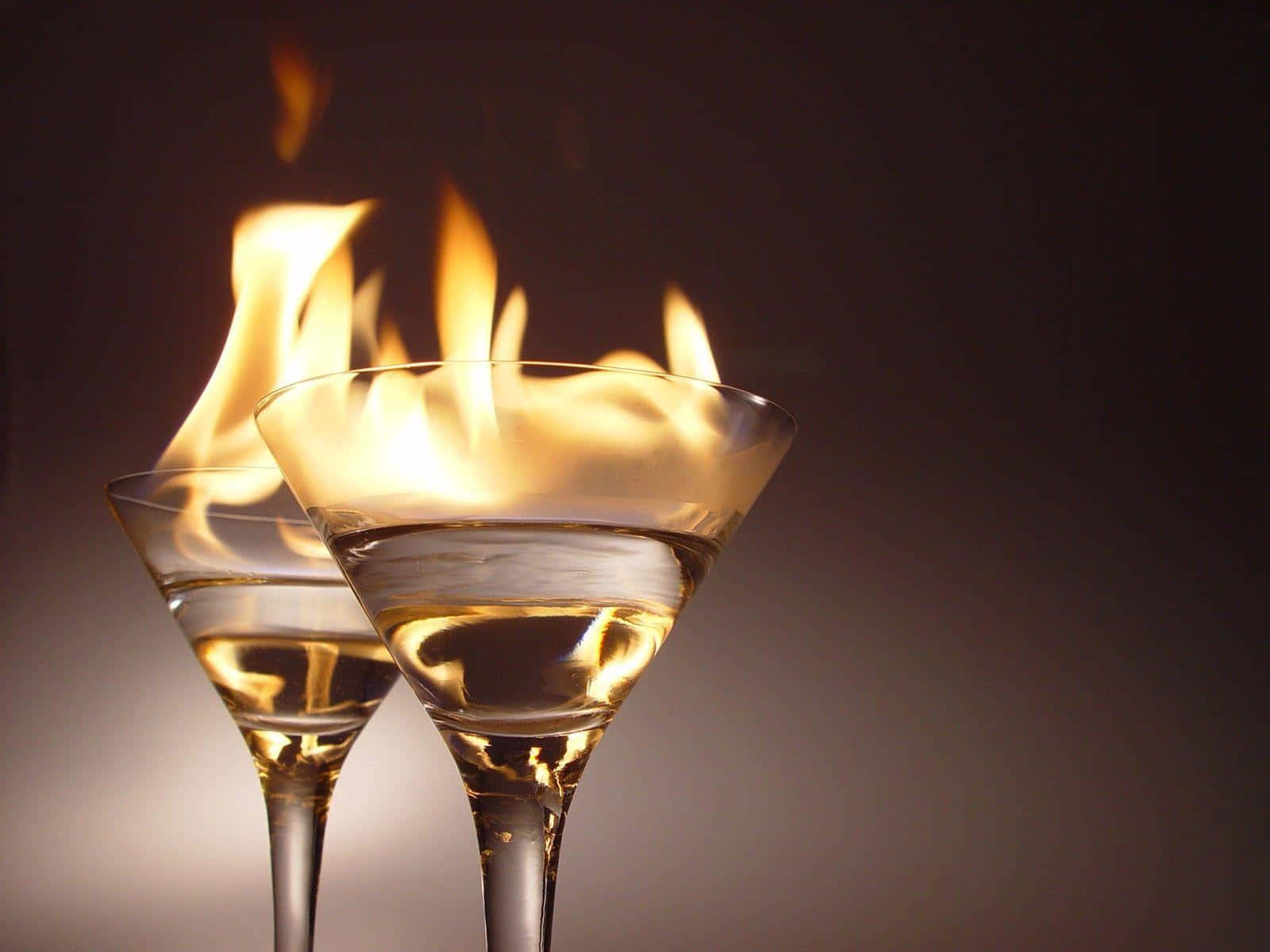 alcohol 桌布 壁紙 — 兩個馬丁尼杯裝滿燃燒的金色液體，背景為深色漸變。