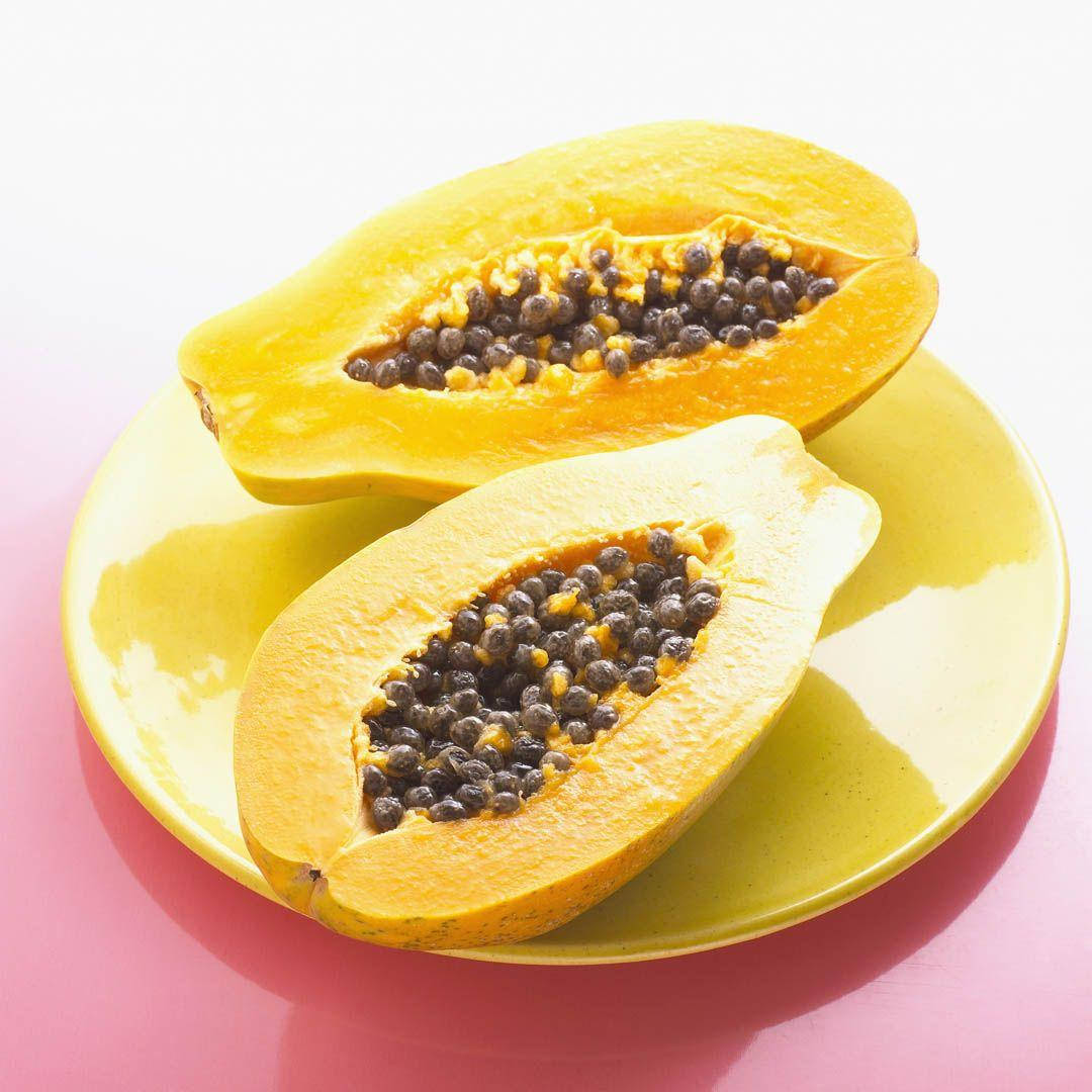 Fruits 桌布 壁紙 — 兩個鮮黃色的木瓜切開，露出黑色種子，放在相配的盤子上，背景是柔和的粉紅色。