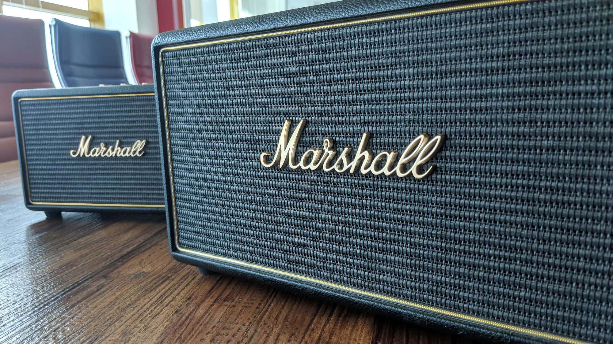 Marshall 桌布 壁紙 — 兩個黑色Marshall揚聲器帶金色飾邊，放在舒適房間的木桌上。