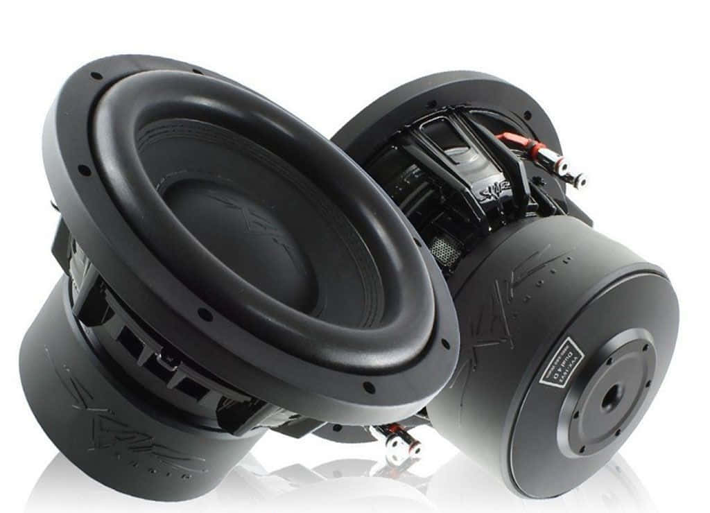 Car Audio 桌布 壁紙 — 兩個黑色超低音喇叭傾斜放置在白色背景前，展示其內部組件和接線。