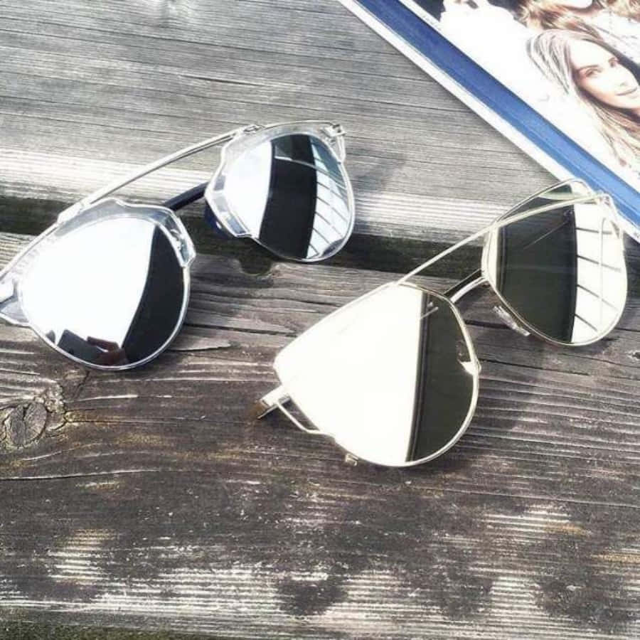 Sunglasses 桌布 壁紙 — 兩副鏡面飛行員太陽眼鏡放在經風化的深色木頭上，旁邊有一本印有女性臉孔的雜誌。