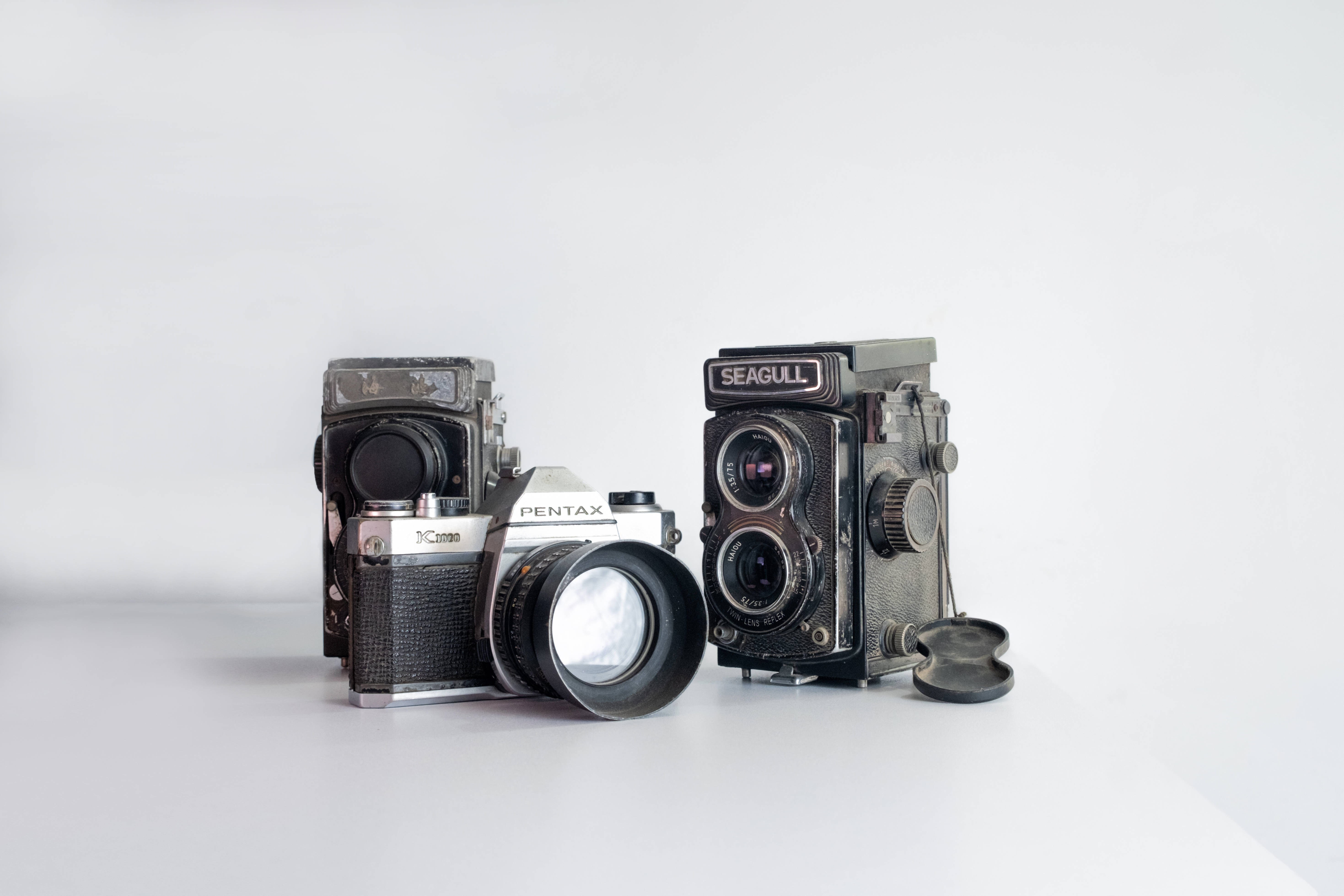 Vintage Minimalist 桌布 壁紙 — 兩台復古雙鏡反光相機，一台Pentax和一台Seagull，並排放在潔白的表面上。