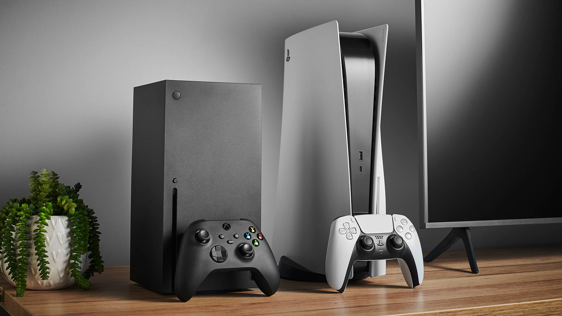 PS5 動態圖片 桌布 壁紙 — 兩台現代遊戲主機Xbox Series X和PlayStation 5並排放在木架上，旁邊有控制器和盆栽植物。