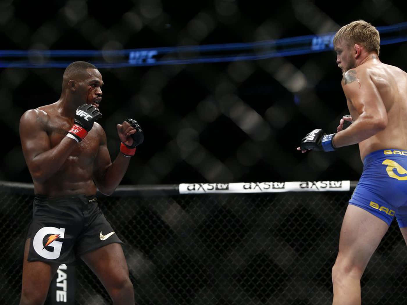 UFC 桌布 壁紙 — 兩名MMA拳手在UFC八角籠內激烈對峙，汗水在他們肌肉發達的身體上閃閃發光。