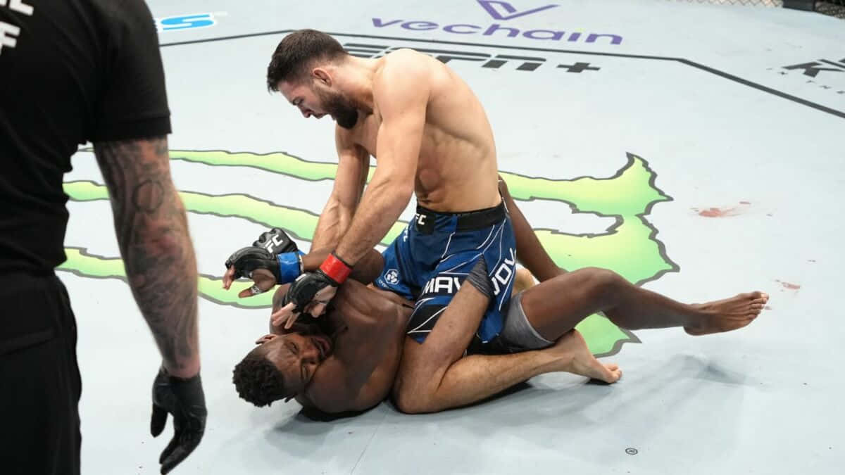UFC 桌布 壁紙 — 兩名MMA拳手在UFC八角籠墊上激烈纏鬥，附近有裁判。