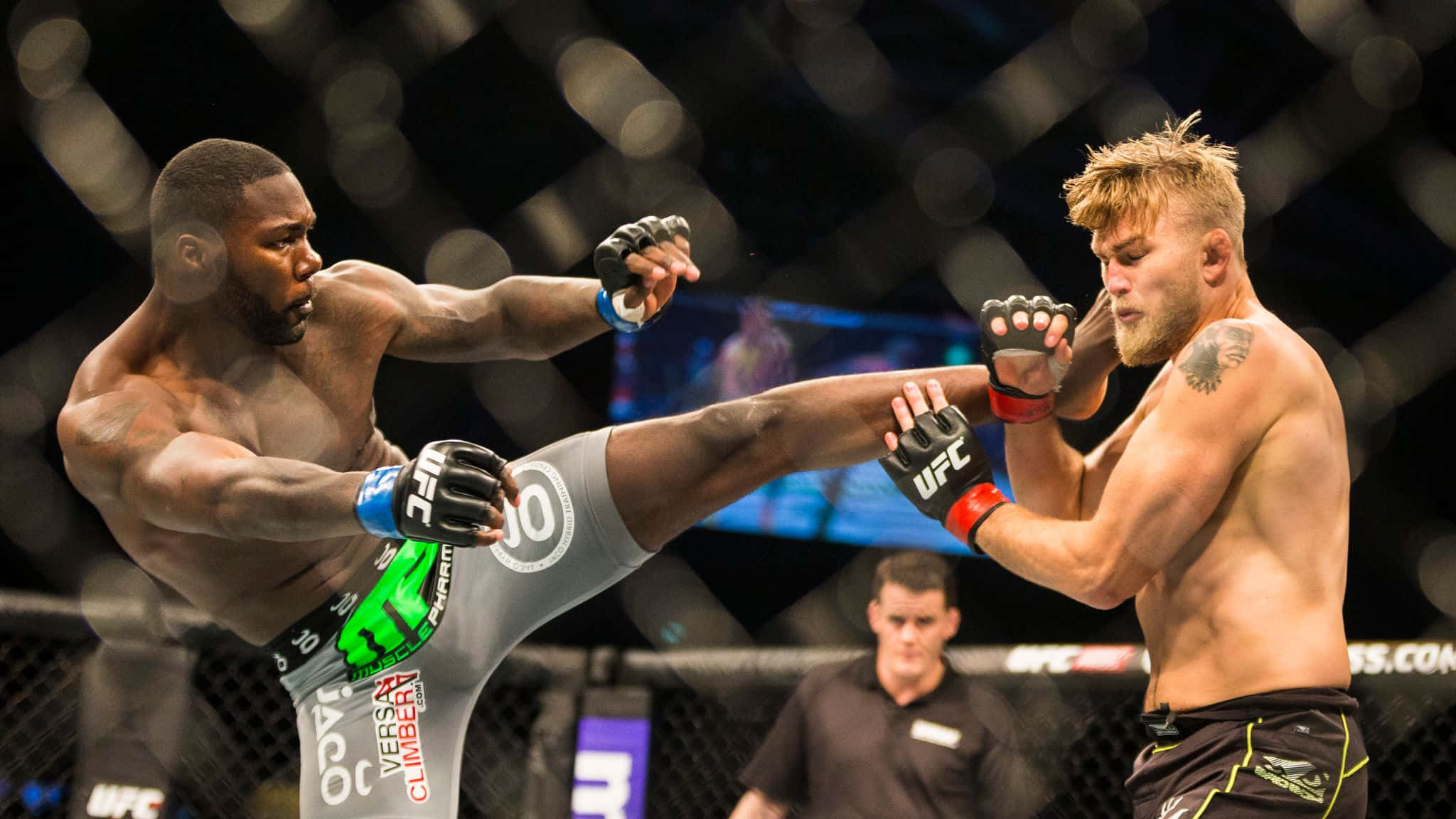 MMA 桌布 壁紙 — 兩名MMA拳手在八角籠中交鋒，一人使出高踢，另一人在明亮的場館燈光下阻擋。