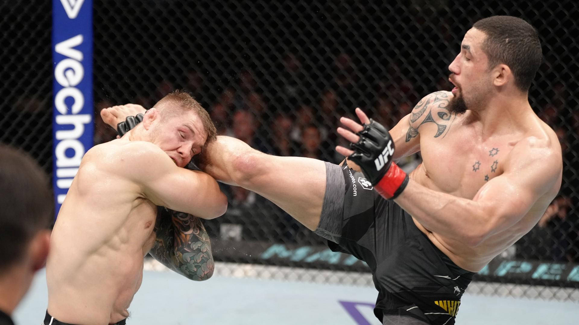 MMA 桌布 壁紙 — 兩名MMA拳手在八角籠中交鋒，一人使出高踢，另一人則在緊張的戰鬥時刻防守。