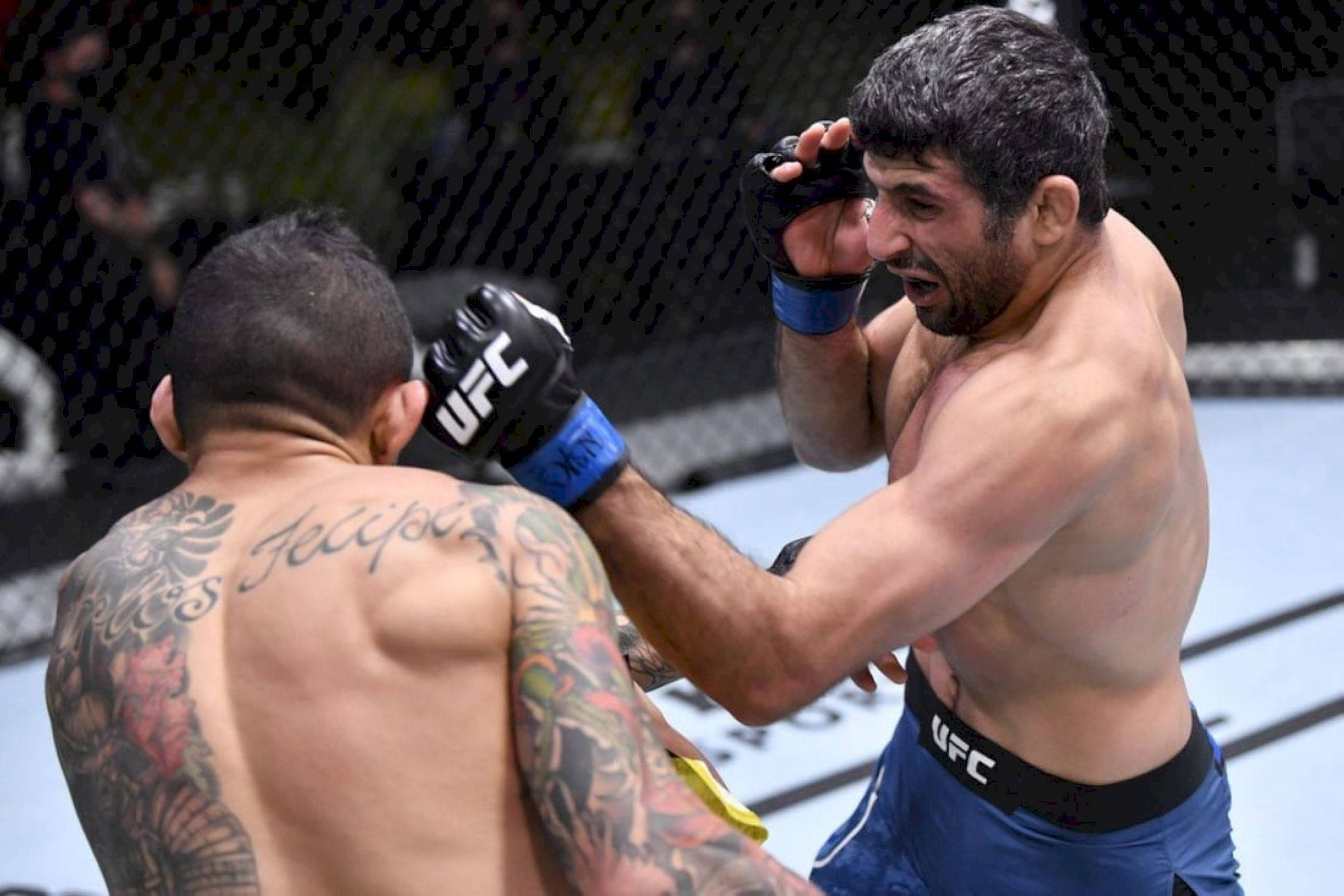 MMA 桌布 壁紙 — 兩名MMA拳手在八角籠中交鋒，其中一拳擊中對方背部，在明亮的場館燈光下顯露刺青。