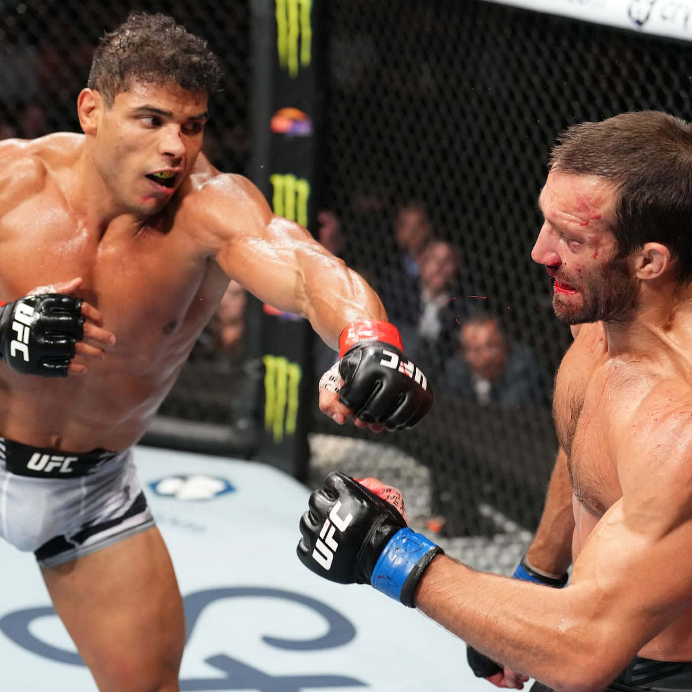 MMA 桌布 壁紙 — 兩名MMA拳手在激烈的籠中賽中交鋒，滿臉鮮血，汗水在明亮的場館燈光下閃閃發光。
