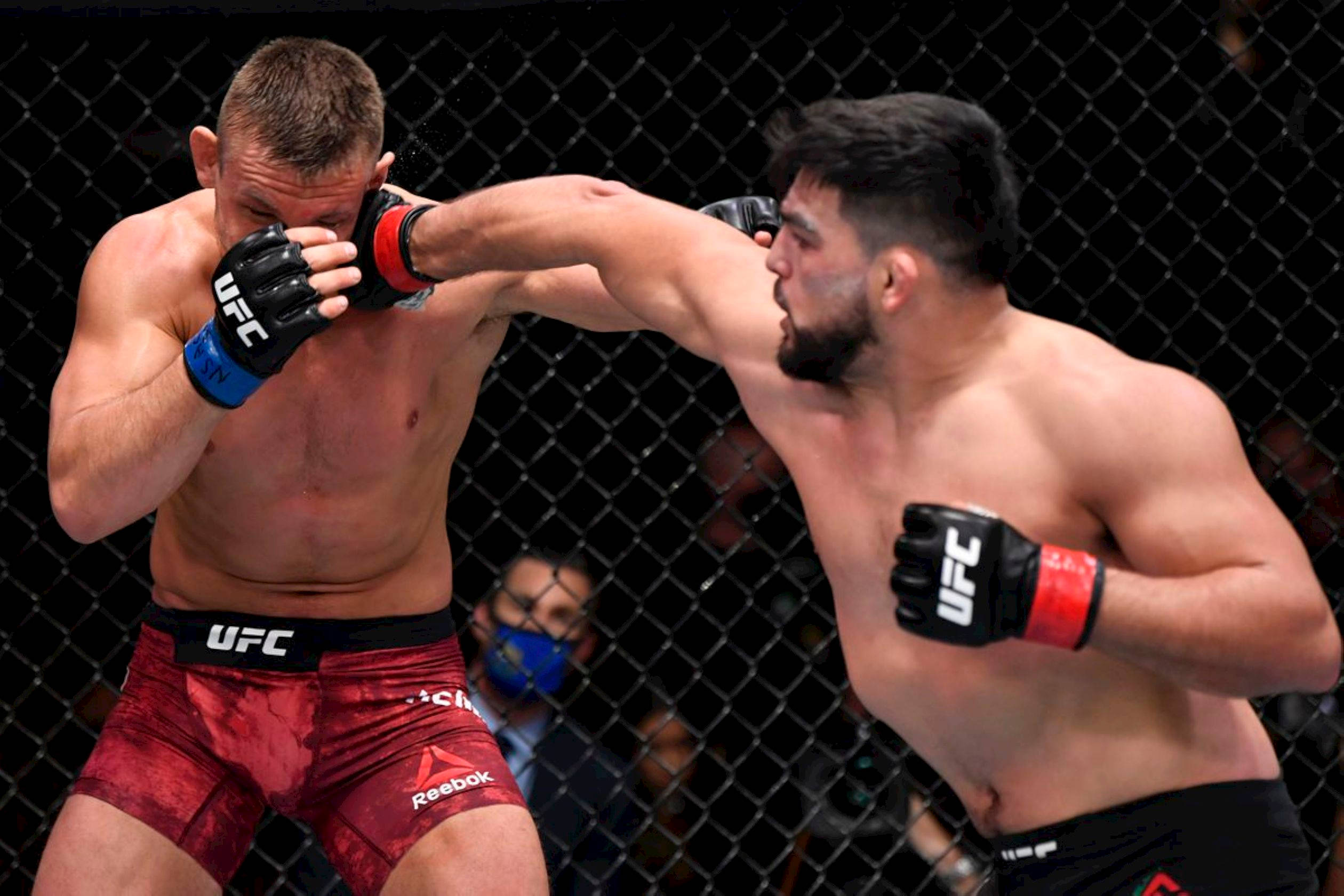 MMA 桌布 壁紙 — 兩名MMA拳手在激烈的籠鬥中交鋒，其中一人向對手面部打出強力一拳。