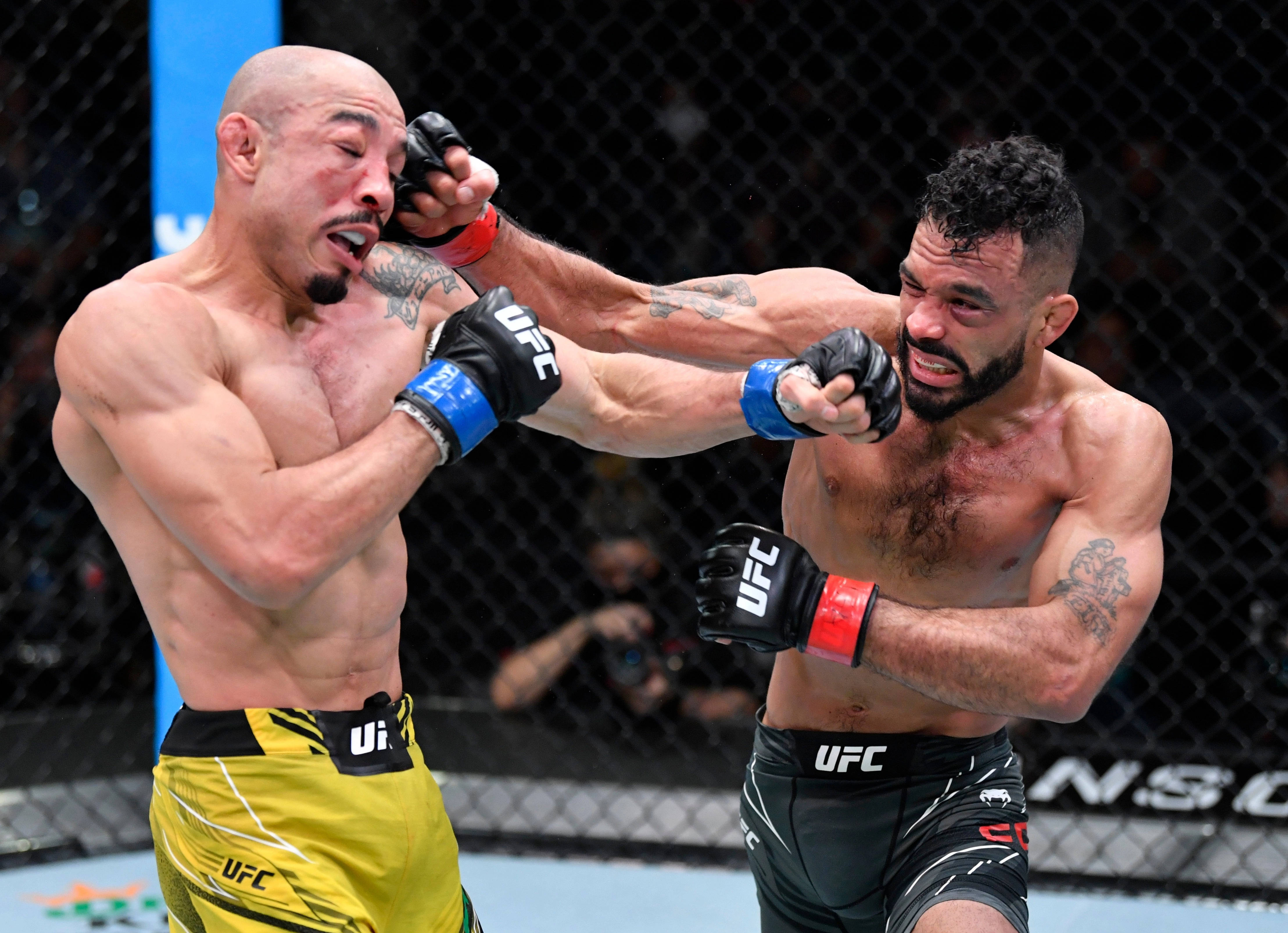 MMA 桌布 壁紙 — 兩名MMA拳手在激烈的鐵籠賽中交鋒，汗水飛濺，表情兇猛，在明亮的場館燈光下。