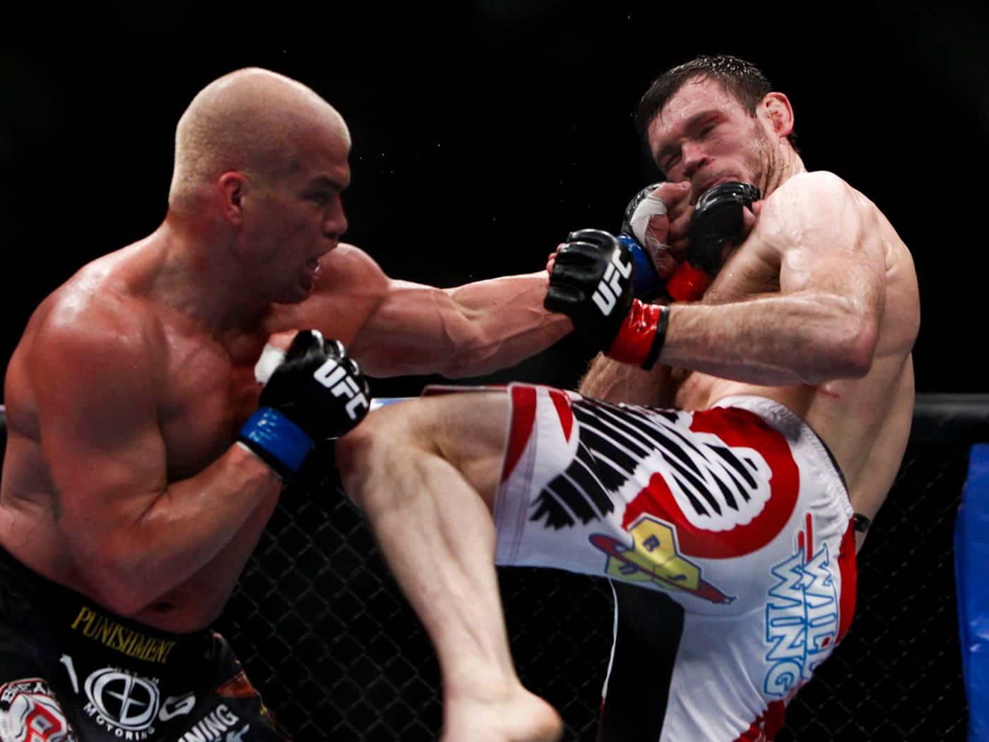 UFC 桌布 壁紙 — 兩名MMA拳手在激烈的鐵籠賽中交鋒，其中一人踢出強力一腳，另一人則防守。