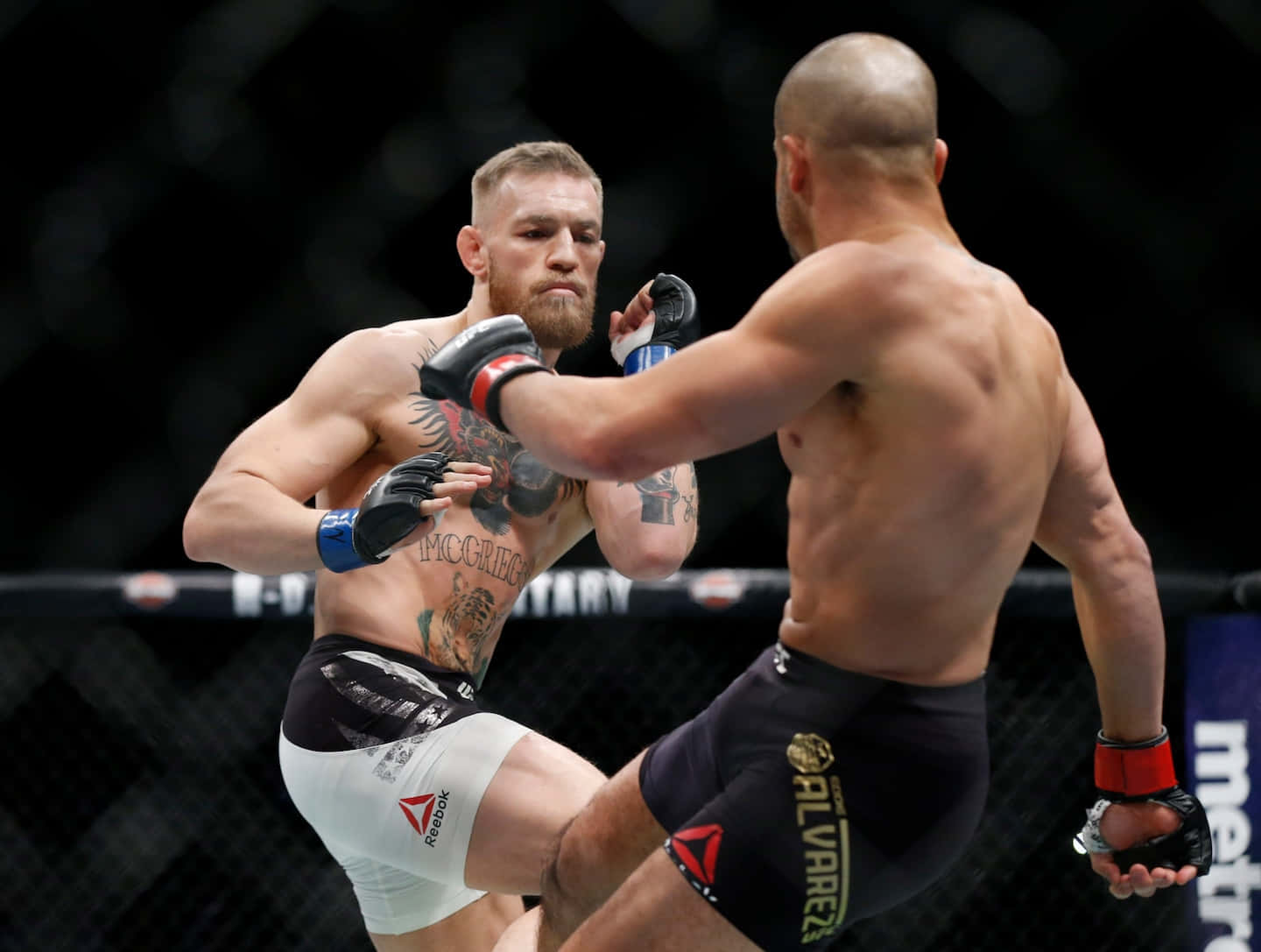 MMA 桌布 壁紙 — 兩名MMA拳手在激烈的鐵籠賽中交鋒，其中一人向對方軀幹踢出強力一腳。