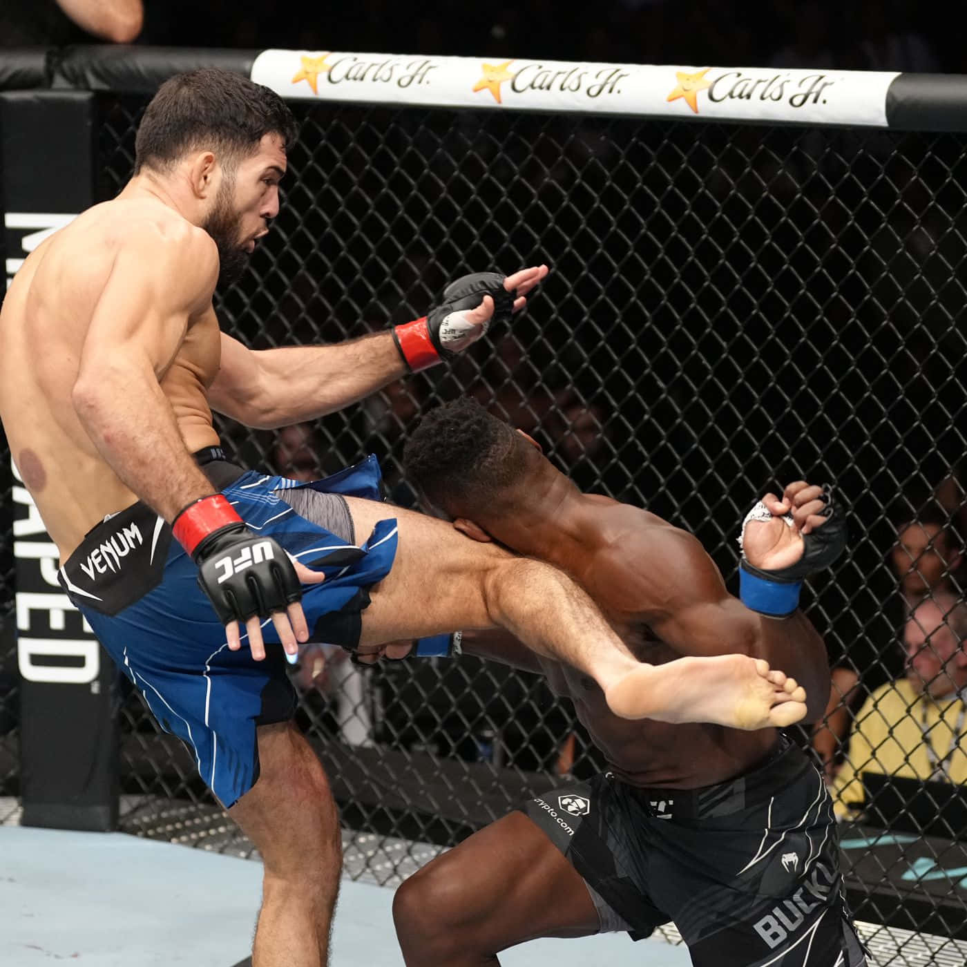 UFC 桌布 壁紙 — 兩名MMA拳手在激烈的鐵籠賽中交鋒，一人使出高踢，另一人防守。