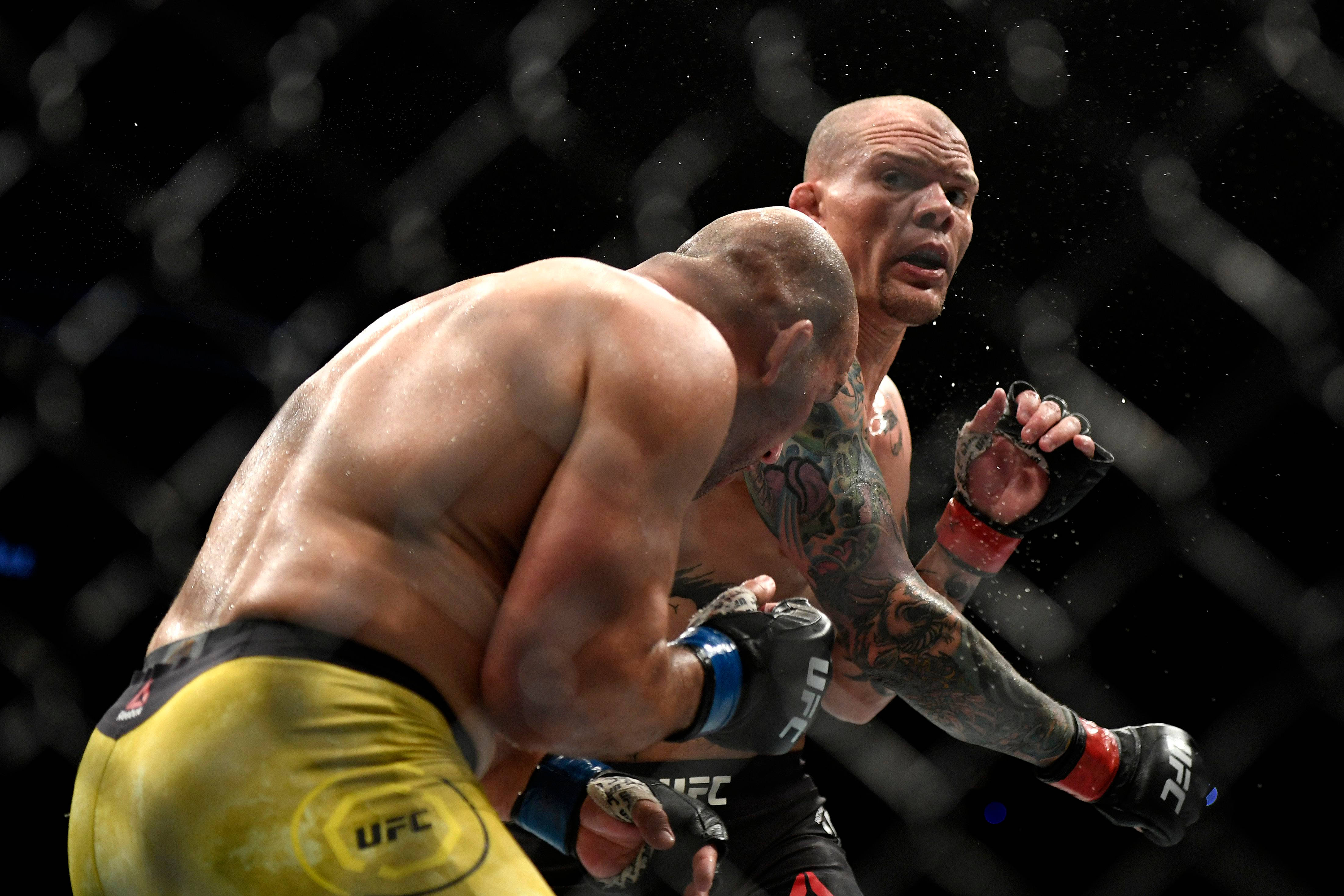 MMA 桌布 壁紙 — 兩名MMA拳手在燈光昏暗的八角籠內激烈碰撞，汗水飛濺，其中一人一拳擊中對手的背部。