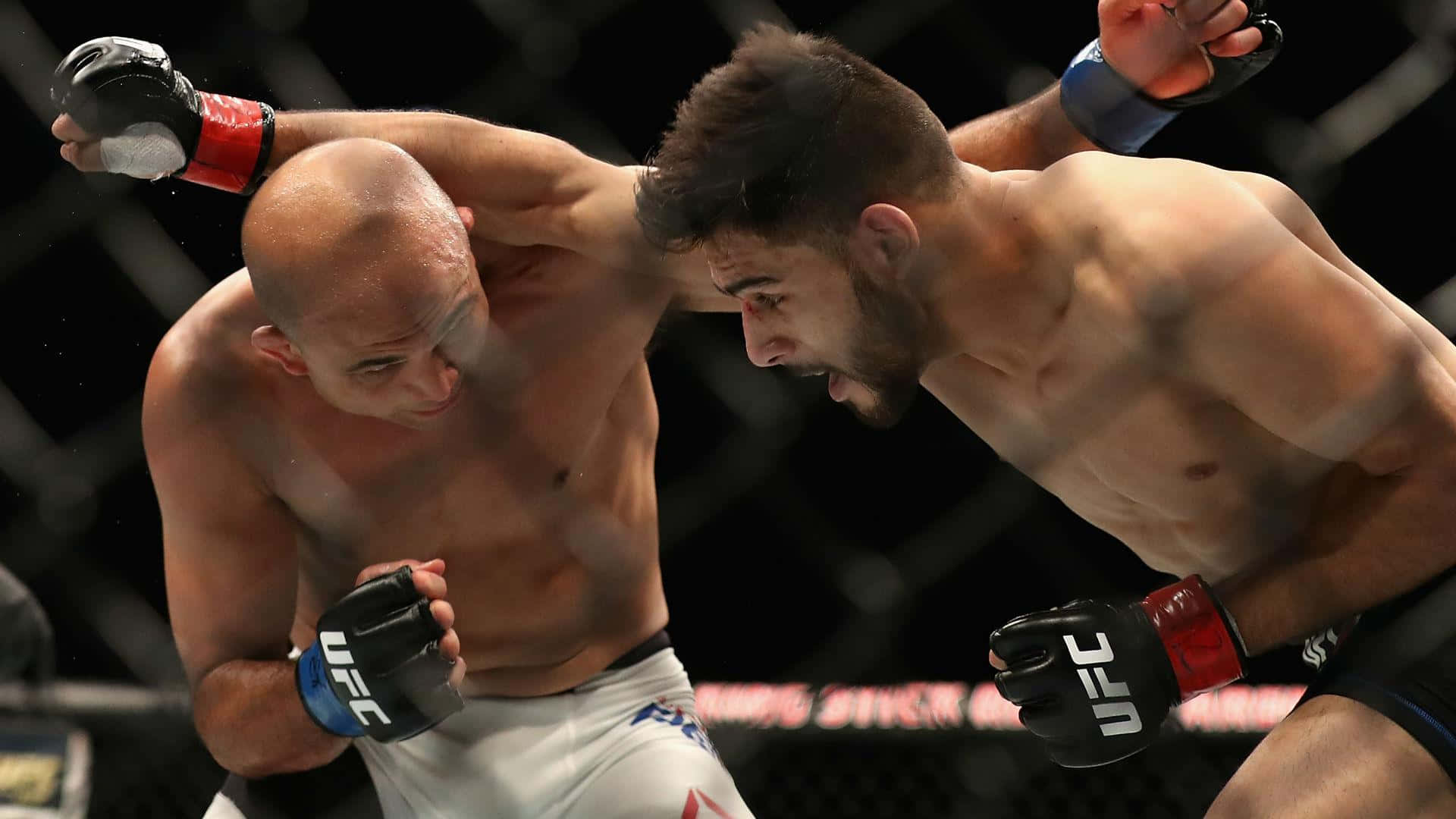 UFC 桌布 壁紙 — 兩名MMA拳手在籠內激烈纏鬥，汗水飛濺，其中一人使出強力肘擊。