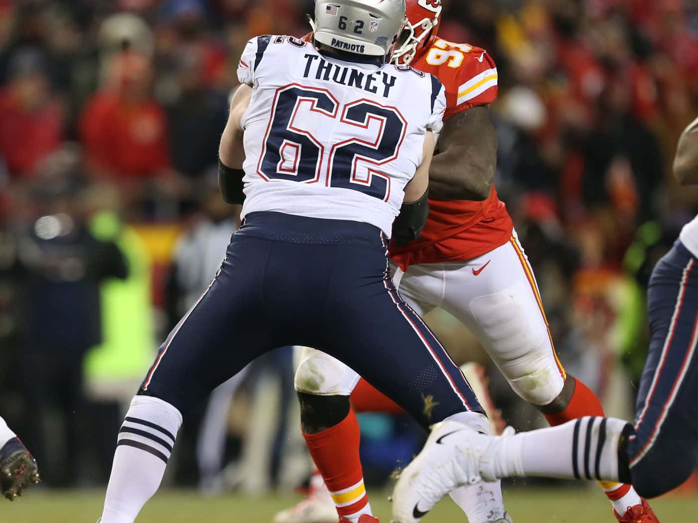 足球 桌布 壁紙 — 兩名NFL進攻鋒線球員在夜間比賽中於球場燈光下進行激烈的身體對抗。