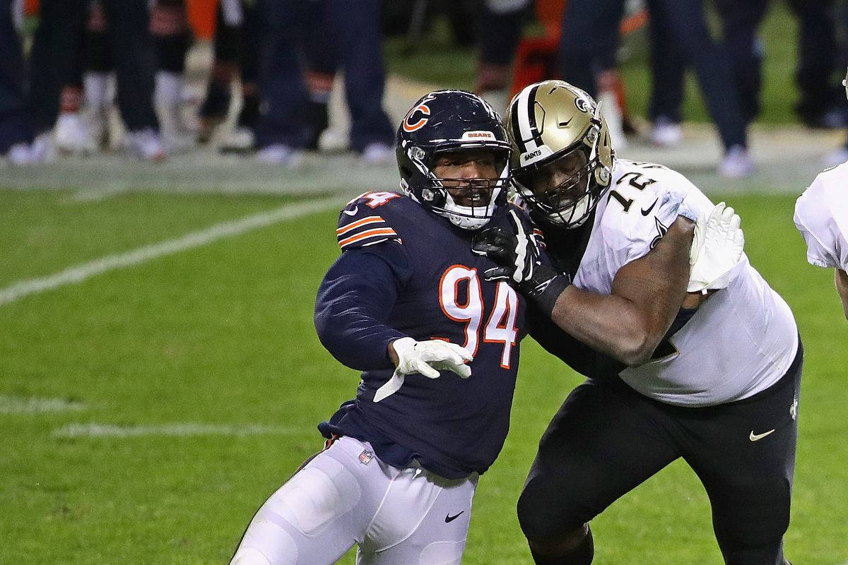 桌布 壁紙 — 兩名NFL鋒線球員戴著頭盔在夜間比賽中於綠色球場上在體育場燈光下激烈纏鬥。