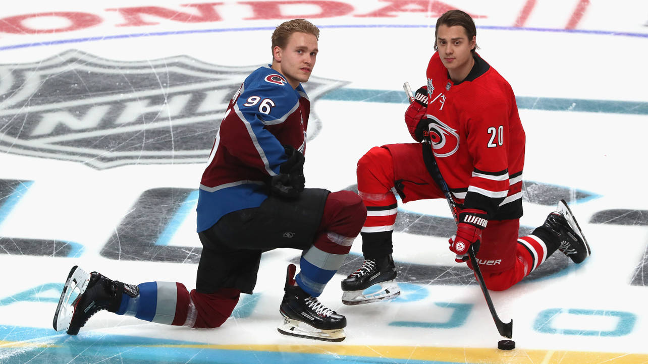 Carolina Hurricanes 桌布 壁紙 — 兩名NHL冰球運動員跪在冰場上，一人身穿棗紅色藍色球衣，另一人身穿紅色球衣，兩人都面帶嚴肅表情向前看。
