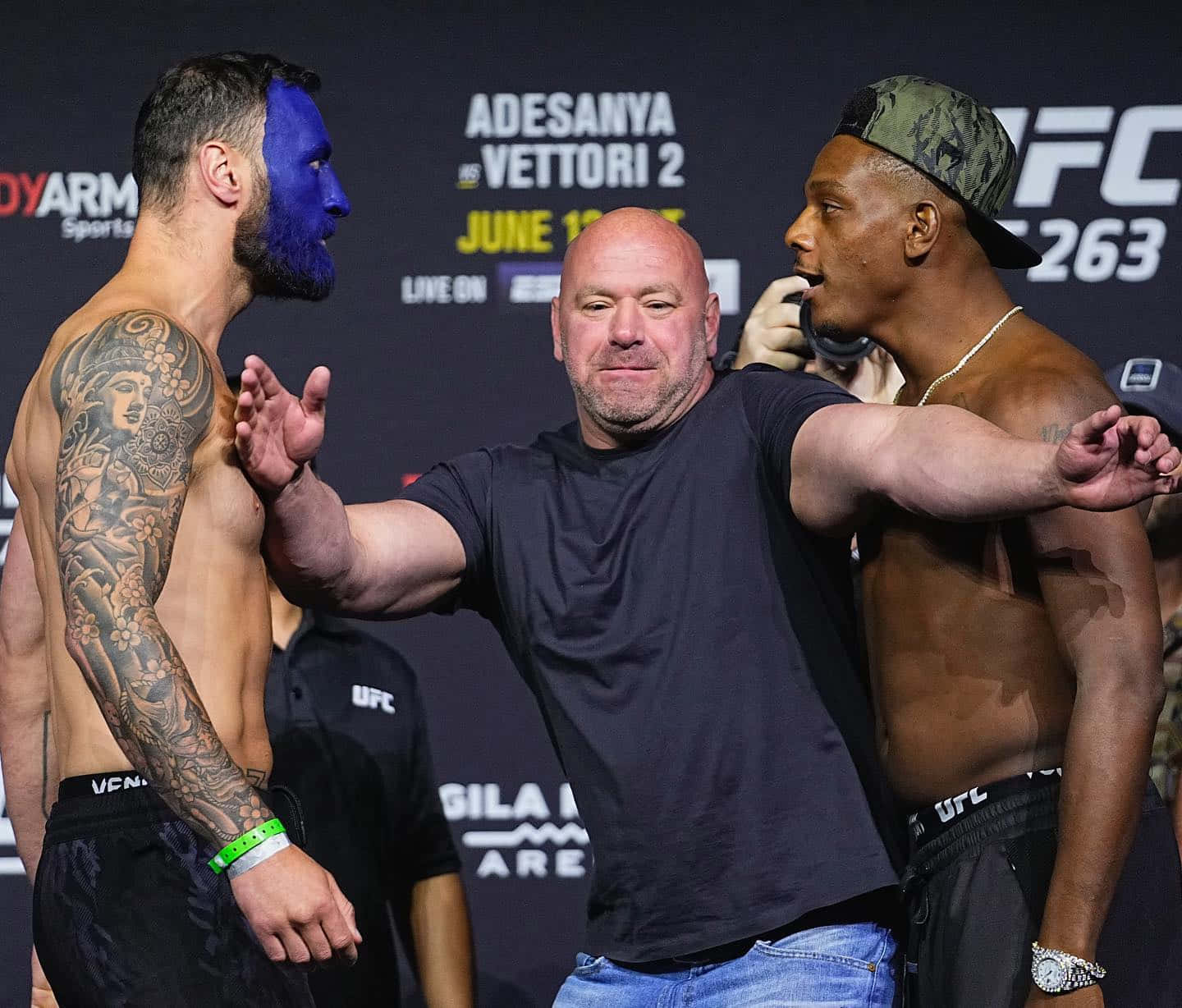 UFC 桌布 壁紙 — 兩名UFC拳手在品牌背景前對峙，裁判將他們分開進行稱重。