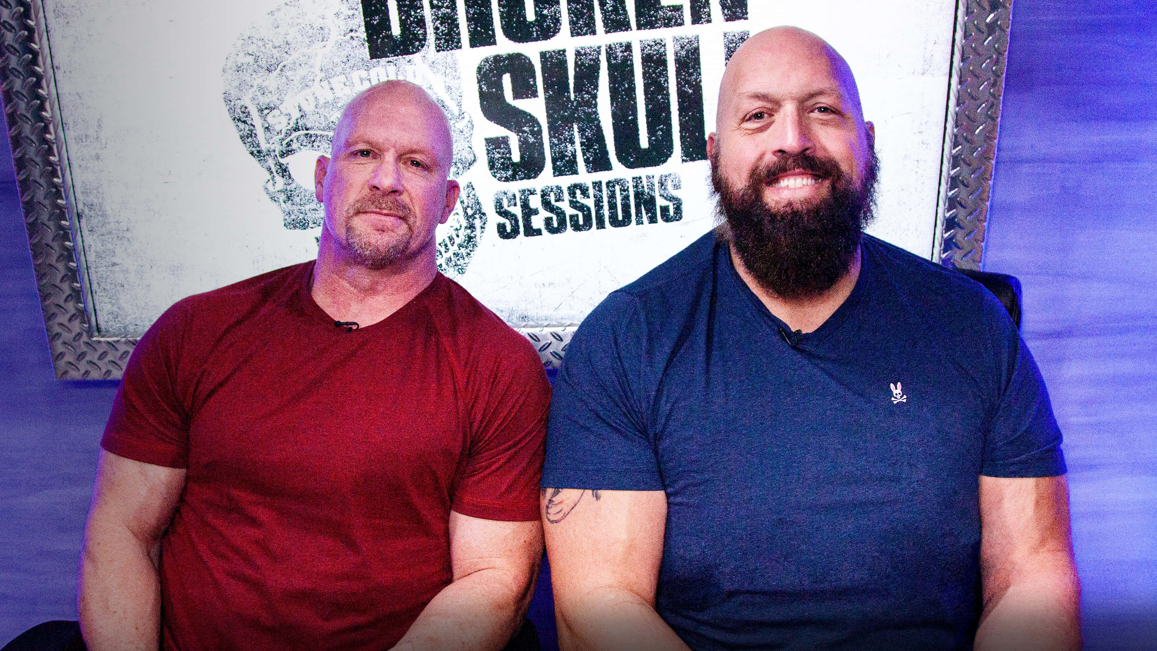 Steve Austin 桌布 壁紙 — 兩名光頭男子，其中一人有鬍鬚，微笑坐在「Broken Skull Sessions」標誌背景前。