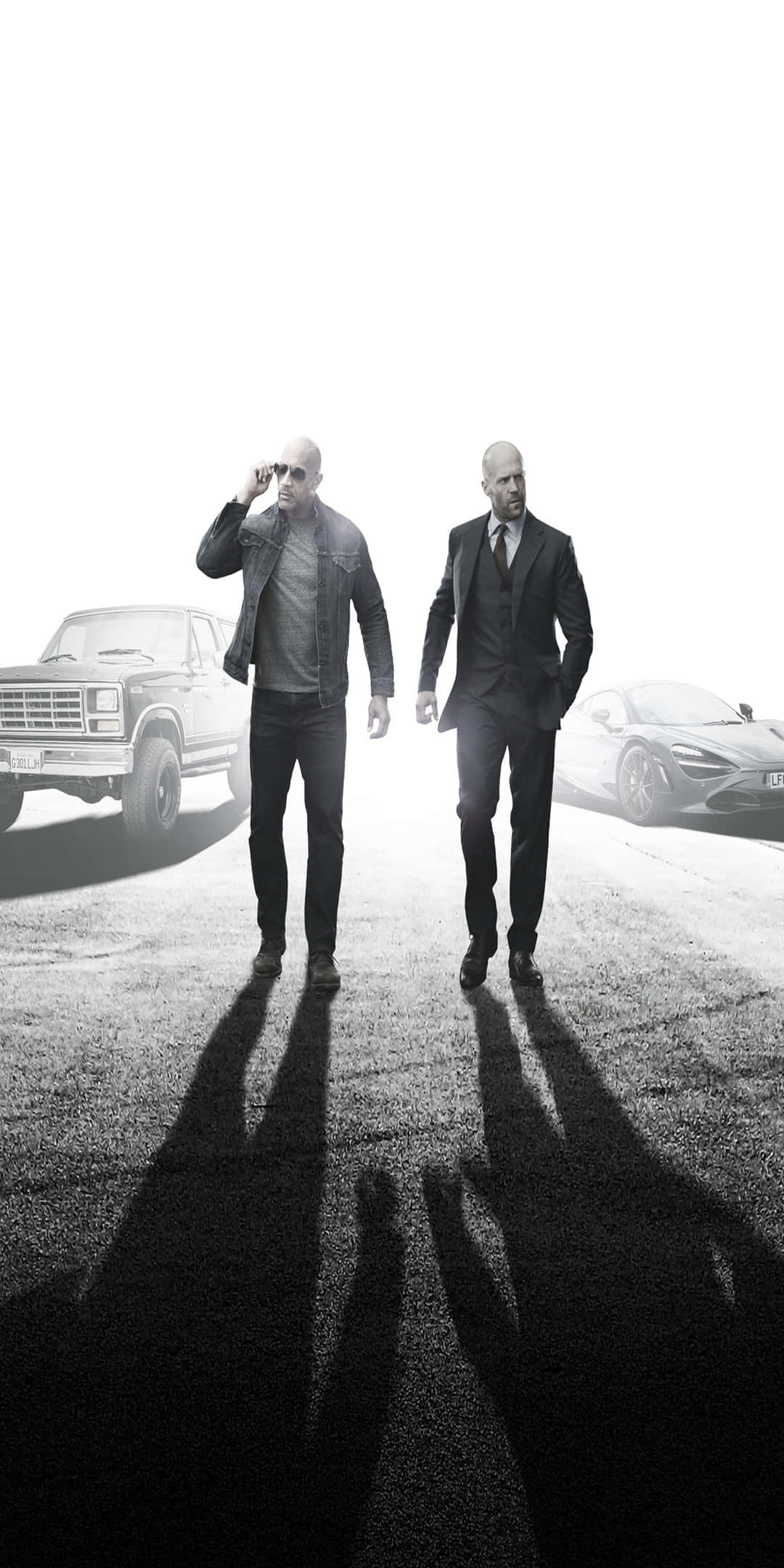 Pixel 3 Fast And Furious 桌布 壁紙 — 兩名光頭男子身穿西裝和休閒服，在柏油路上拖著長長的影子，走向觀眾，旁邊有一輛復古卡車和一輛現代跑車。