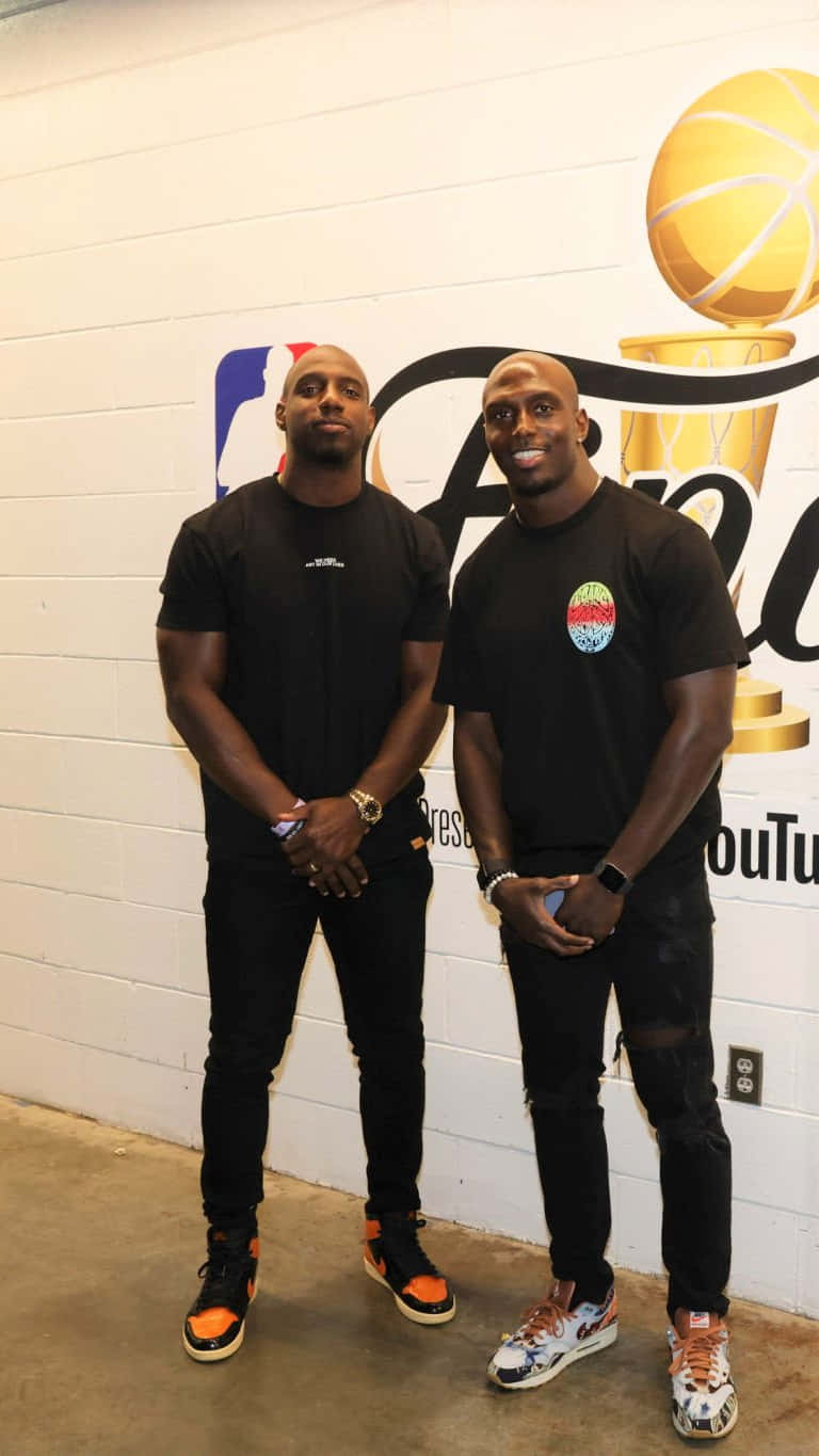 Devin Mccourty 桌布 壁紙 — 兩名光頭男子身穿黑色服裝，在印有NBA總決賽和YouTube標誌的白色牆前自信地擺姿勢。