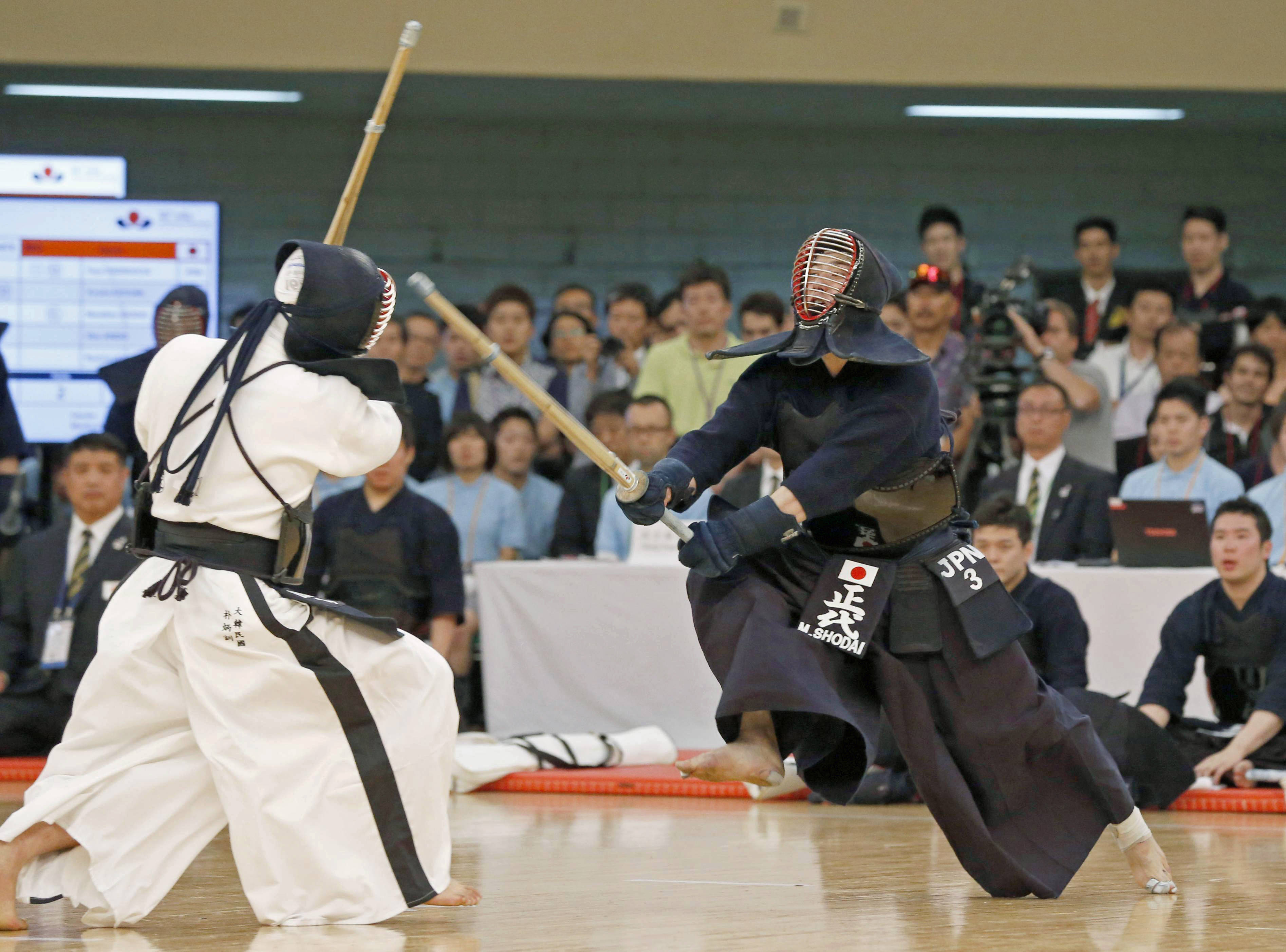 運動 桌布 壁紙 — 兩名全副武裝的劍道鬥士在觀眾面前用竹劍進行緊張的室內比賽。