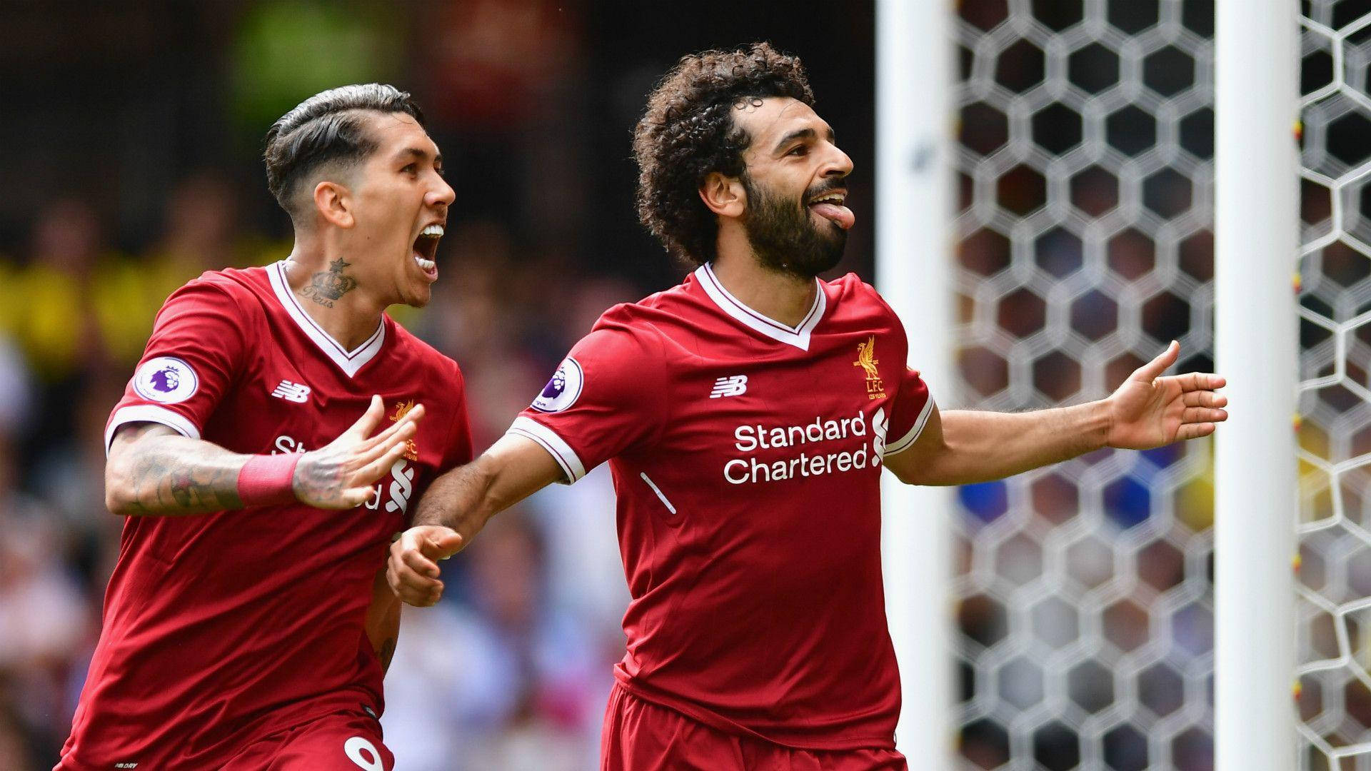 Salah 桌布 壁紙 — 兩名利物浦足球運動員身穿紅色球衣，在六角形球門網附近以狂喜的表情慶祝進球。