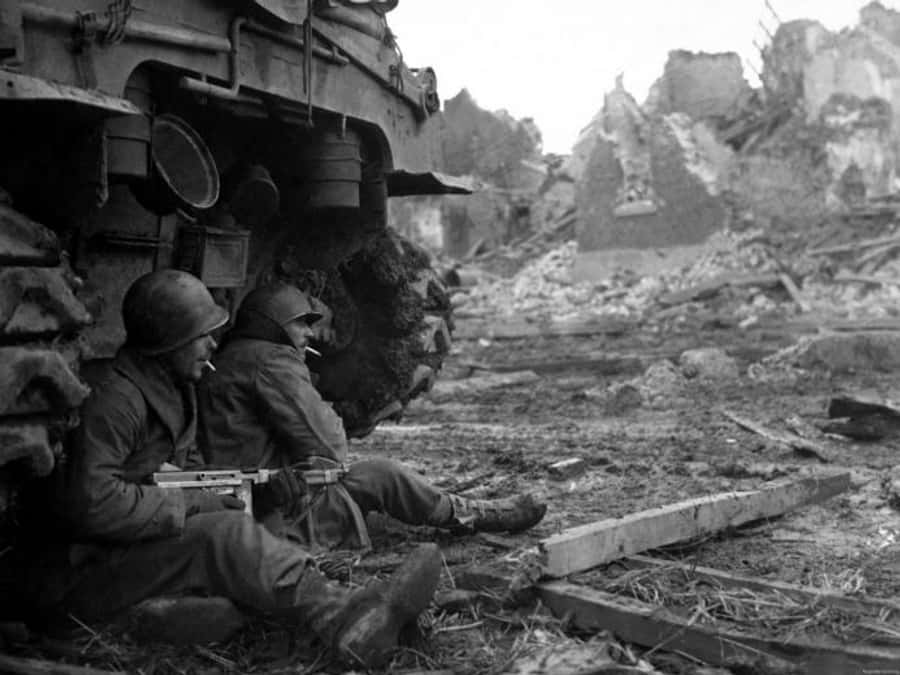 soldier 桌布 壁紙 — 兩名士兵在戰火摧殘的城市景觀中，靠著坦克車在瓦礫中休息。