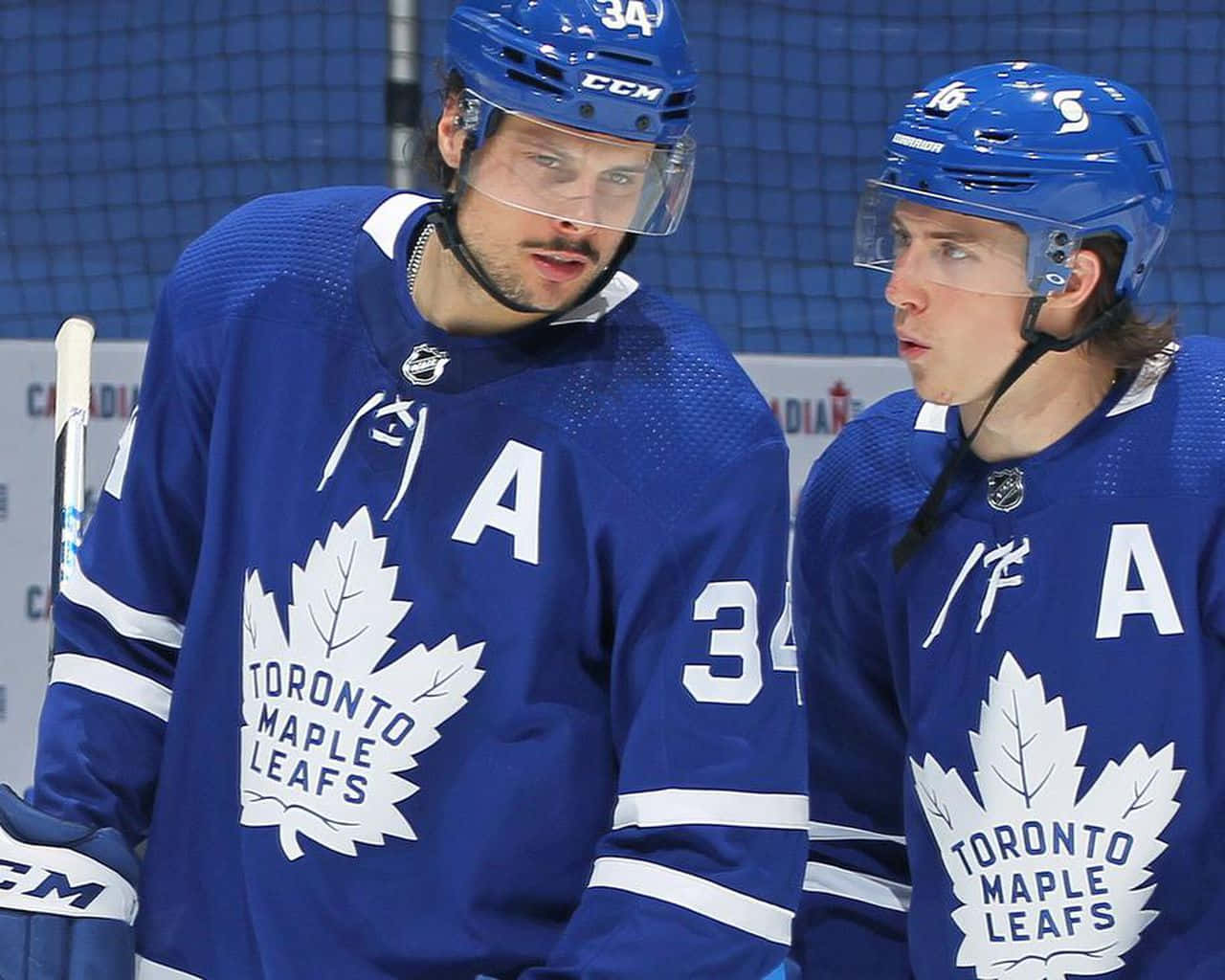 Toronto Maple Leafs 桌布 壁紙 — 兩名多倫多楓葉隊冰球運動員身穿藍色球衣，帶有白色楓葉標誌，在練習期間站在冰上。